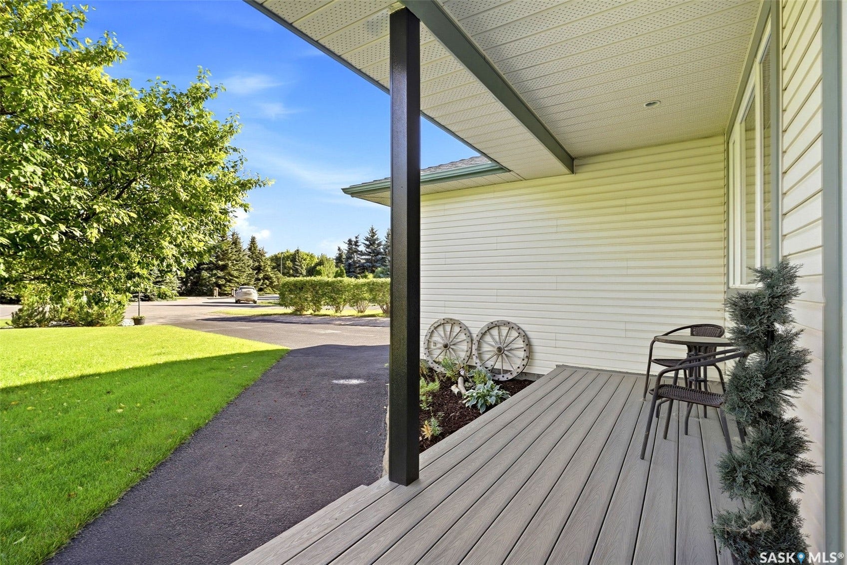 Front porch with composite decking, light-colored siding, and a landscaped planter