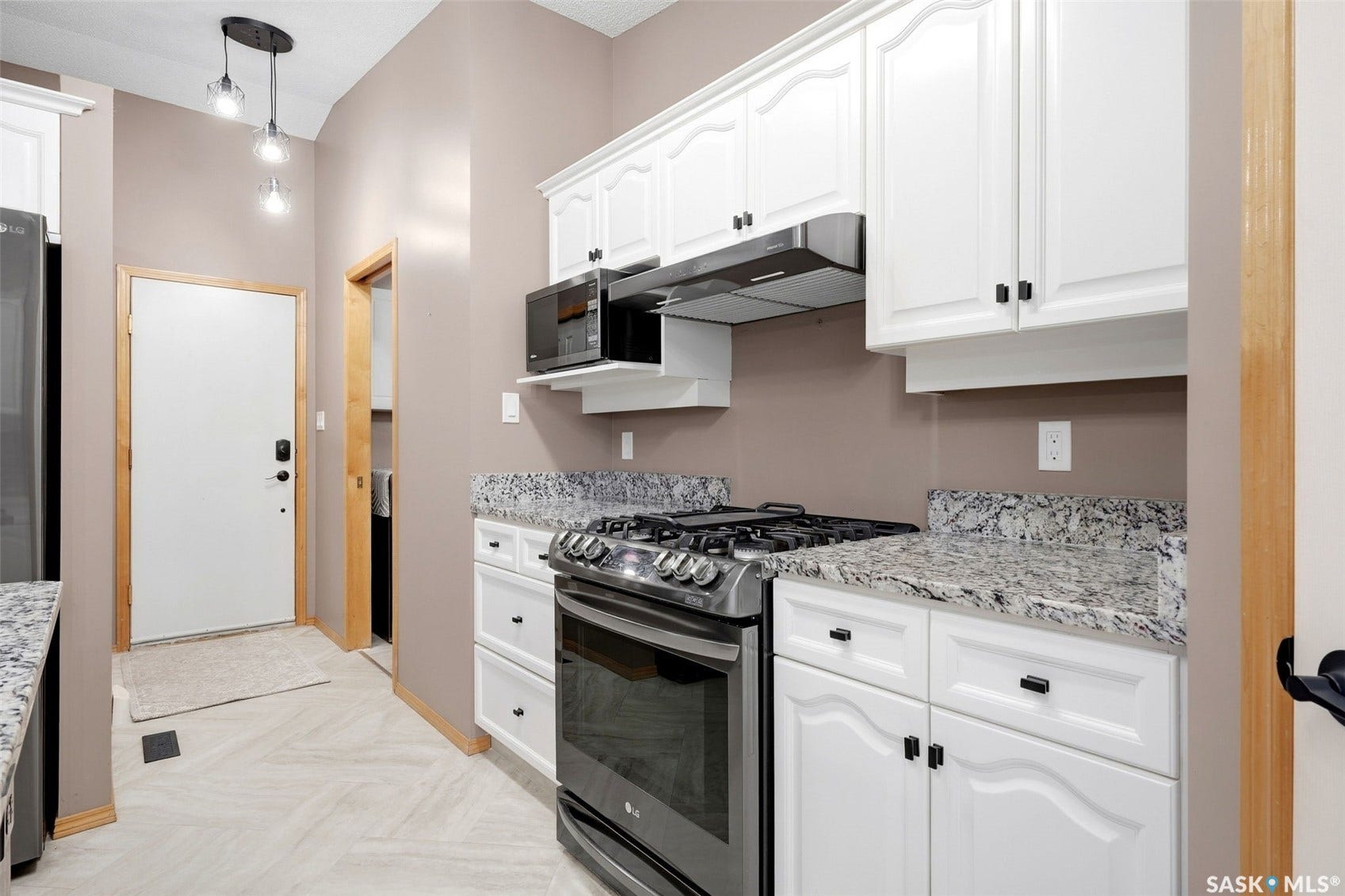 White cabinetry, stone countertops, stainless steel range, built-in microwave, and wood-finish flooring