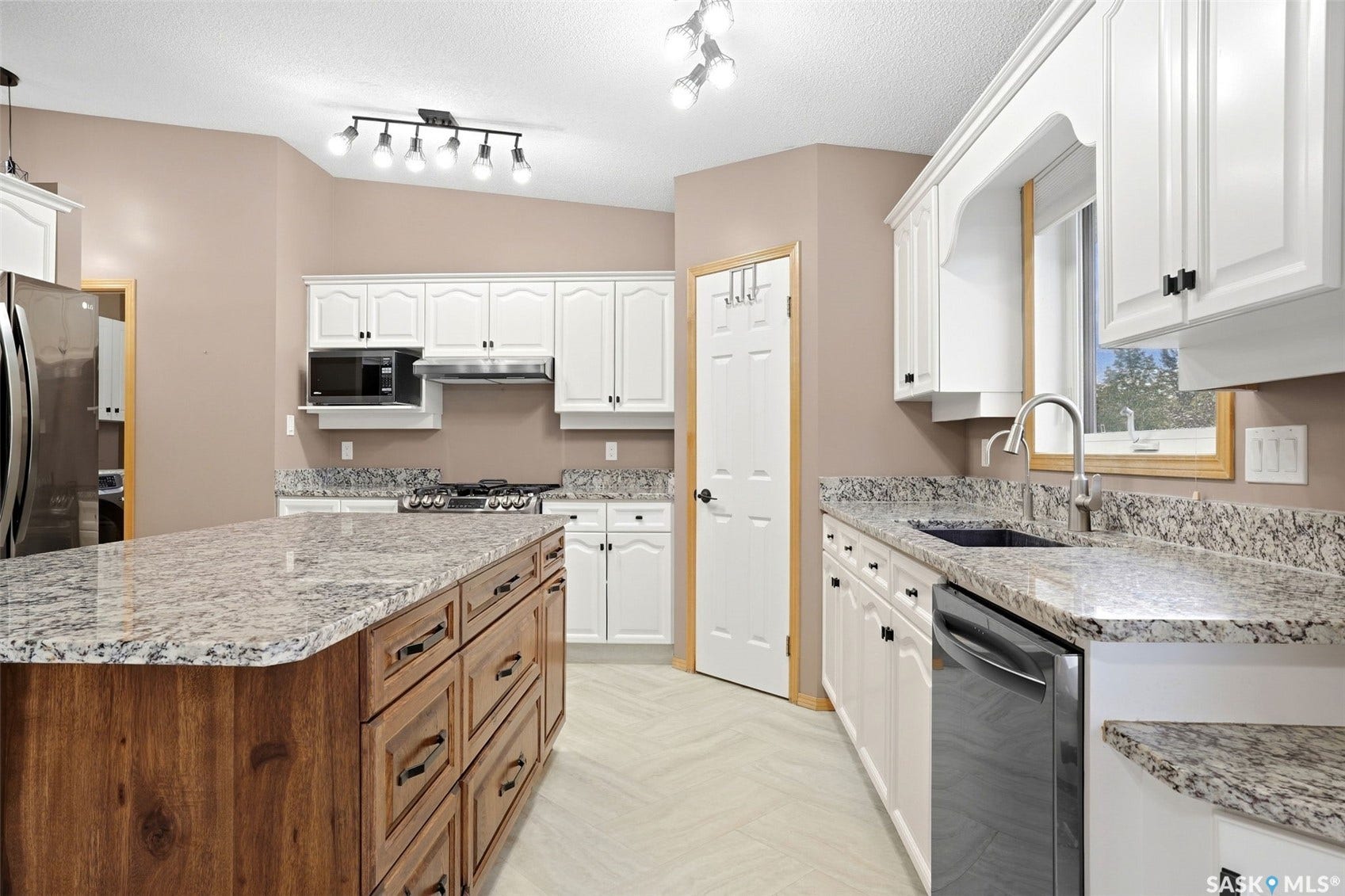 Kitchen with white cabinetry, stainless steel appliances, speckled stone countertops, and a wood-finish island with integrated storage