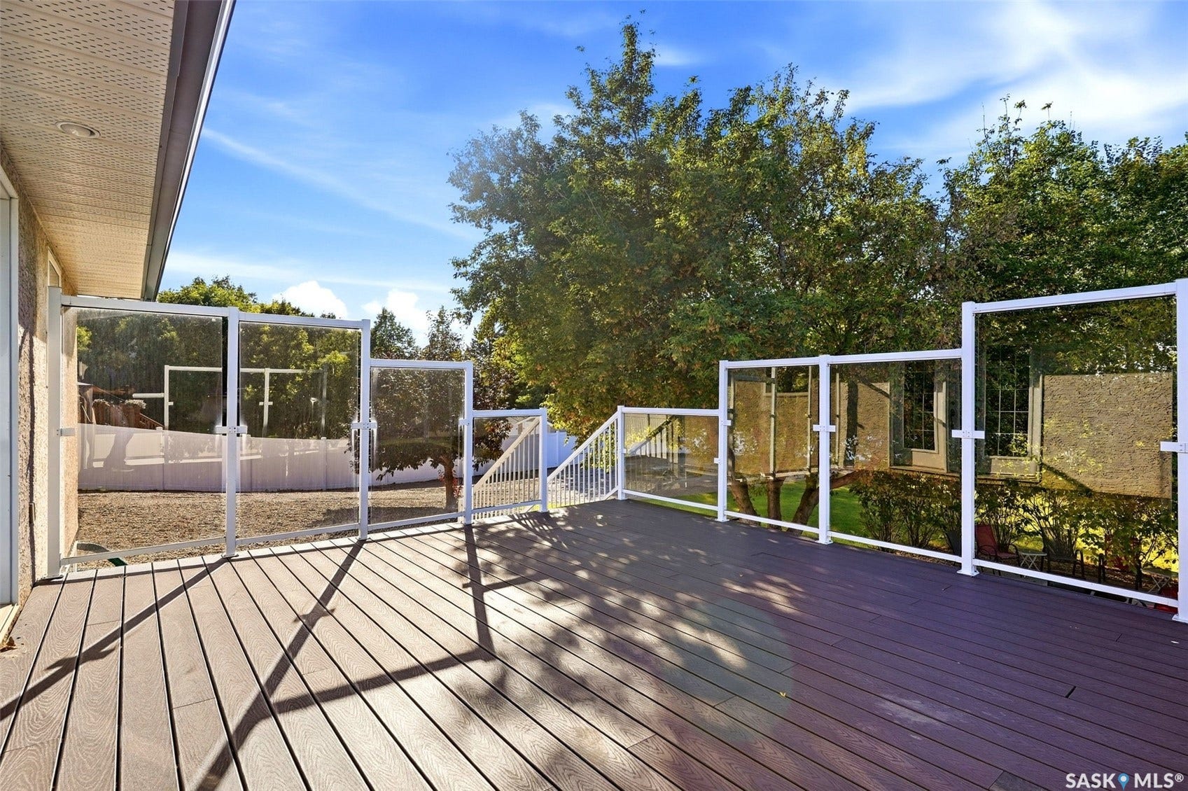 Spacious outdoor deck featuring composite decking, glass panel railings, and white aluminum framing