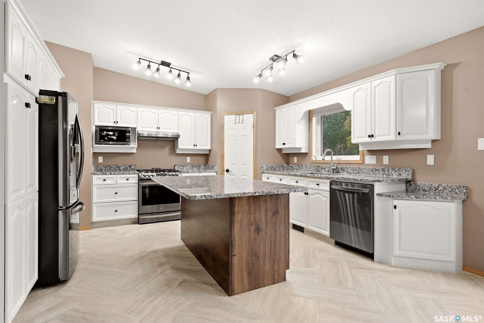 Kitchen featuring white cabinetry, granite countertops, stainless steel appliances, a wood-finish island, and light-toned tile flooring