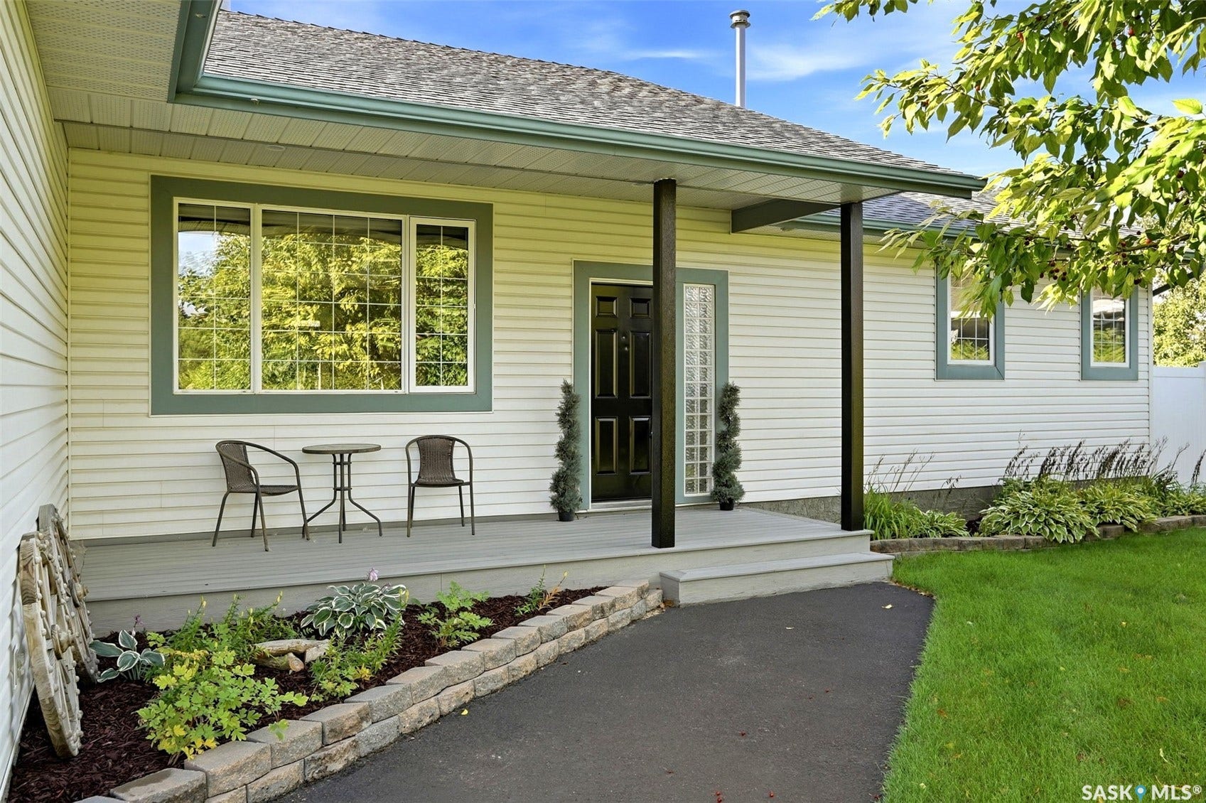 Front porch with a dark wood entry door, grid windows, and a stone retaining wall