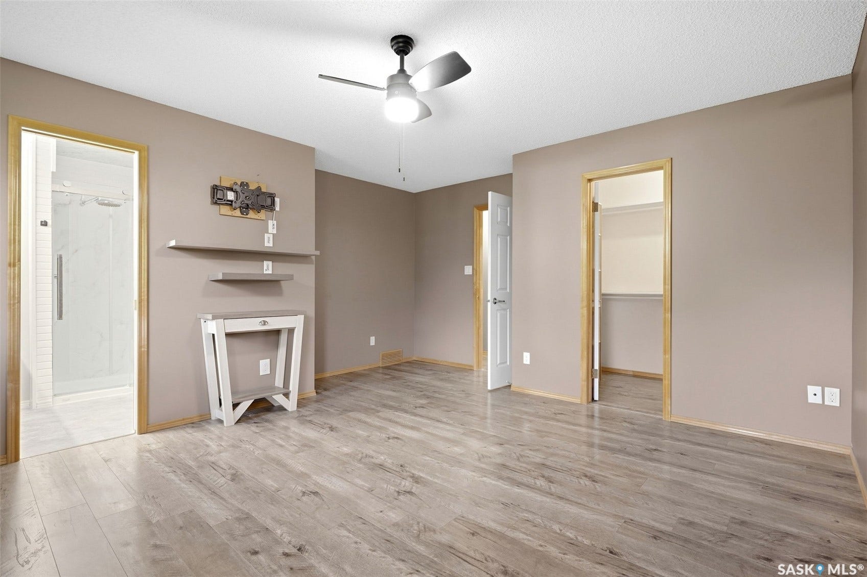 Wood-finish flooring throughout, ceiling fan with integrated lighting, and a walk-in shower with clear glass enclosure