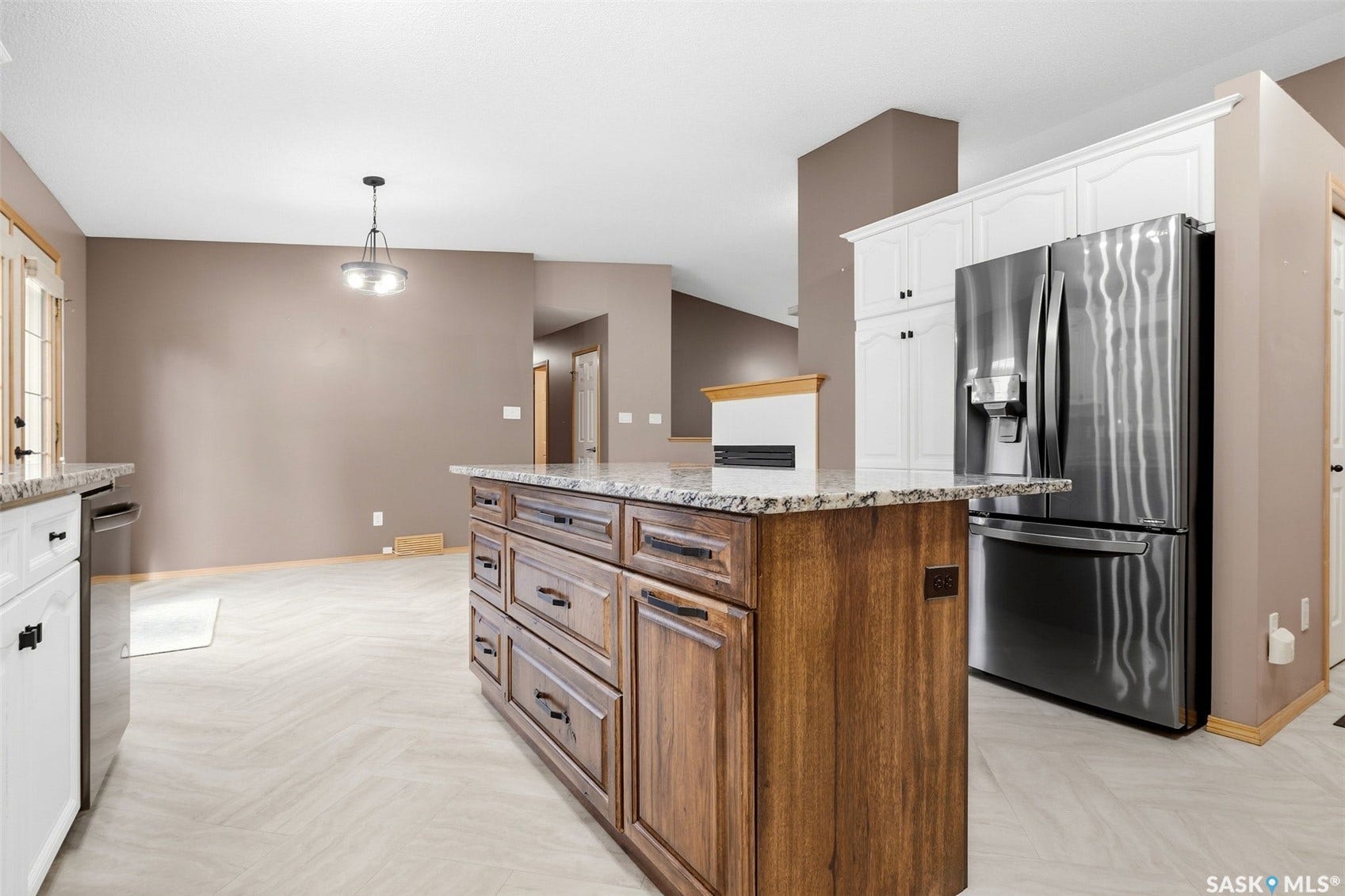 Kitchen featuring a wood-finish island with stone countertops, white cabinetry, a stainless steel refrigerator, and light-toned flooring