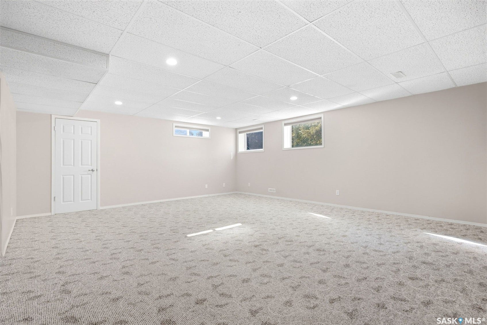 Expansive room with neutral carpet, recessed lighting, drop ceiling, and multiple windows