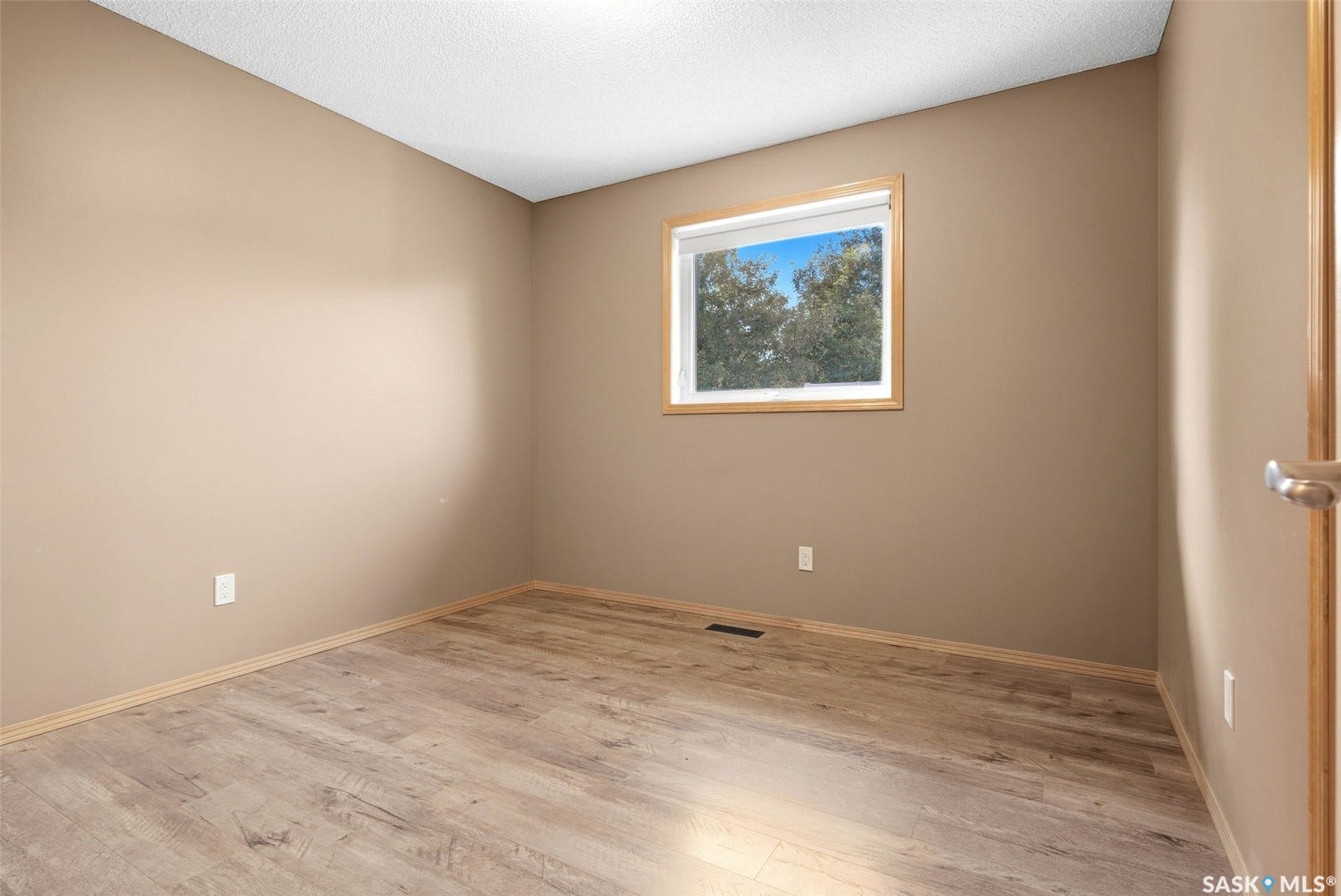 Wood-finish flooring, neutral wall paint, and a window with a wood-finish trim