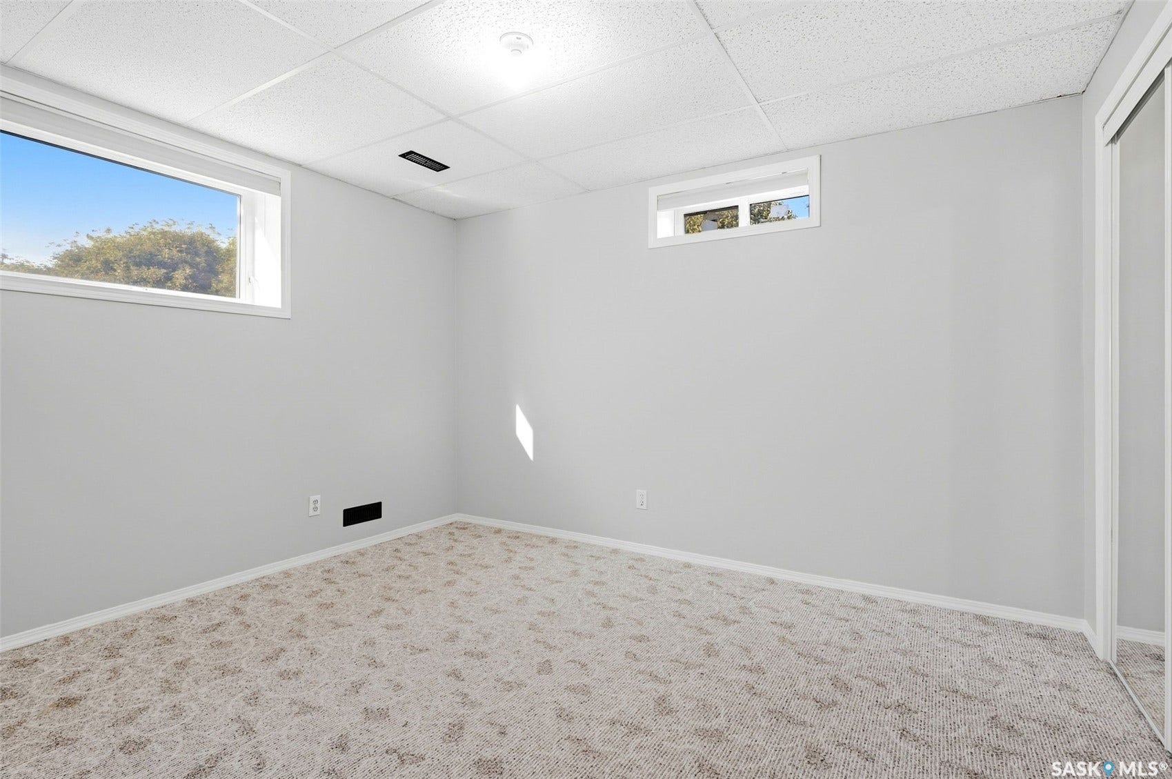 Recessed lighting, drop ceiling, carpeted flooring, mirrored sliding closet doors, and multiple windows