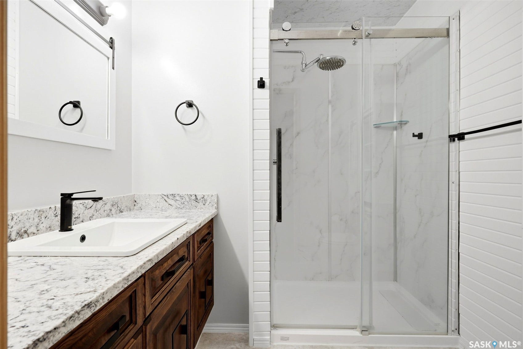 Vanity with a white rectangular undermount sink, a matte black faucet, and a stone countertop