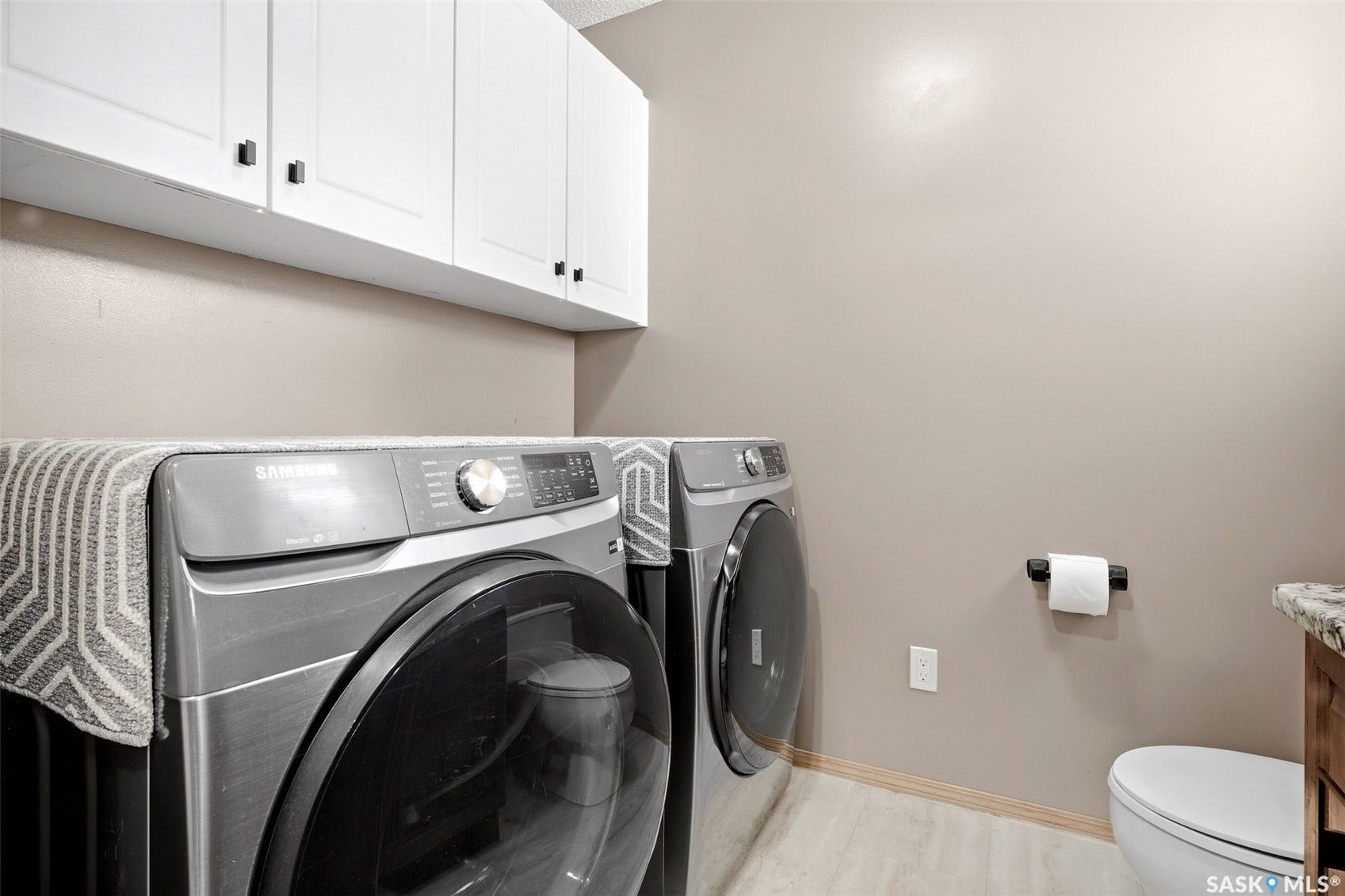 Overhead white cabinetry, neutral wall paint, and light wood-finish flooring