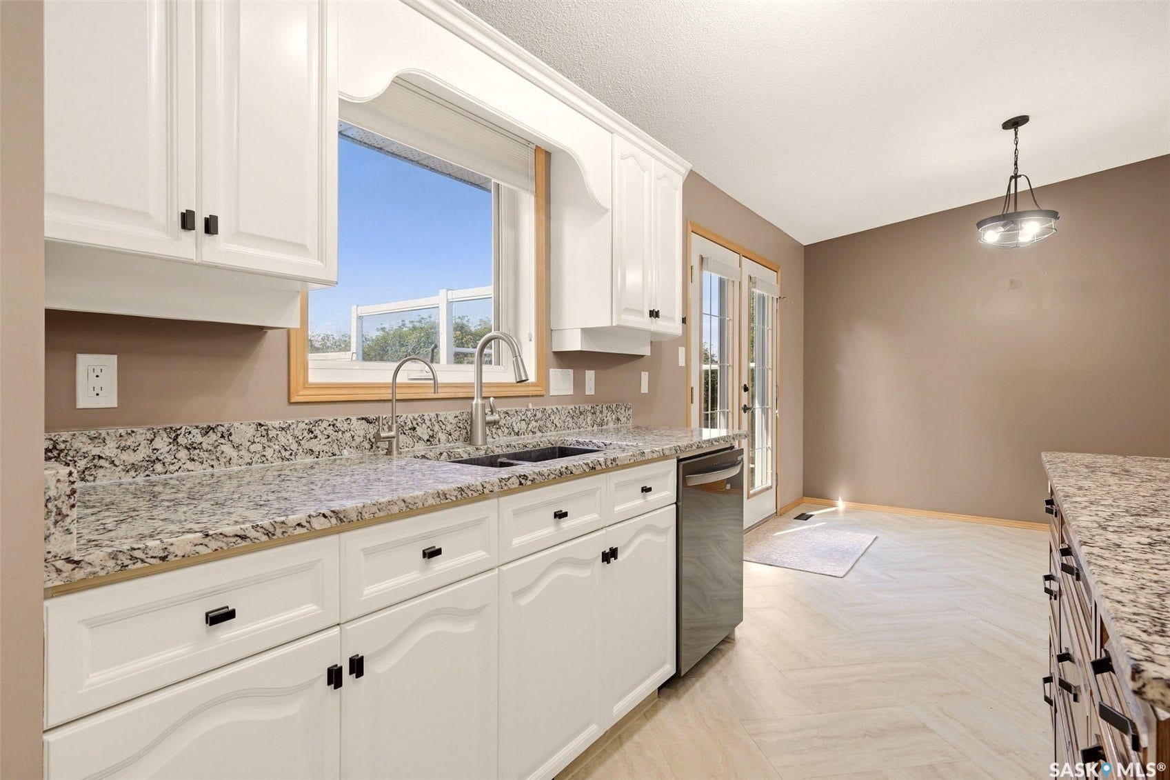White cabinetry with dark hardware, granite-style countertops, stainless steel dishwasher, double basin sink with gooseneck faucet, and light wood-finish flooring