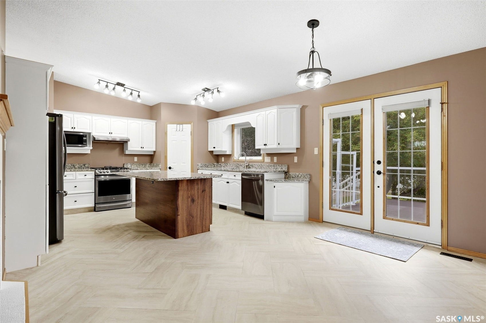 Kitchen featuring wood-finish flooring, white cabinetry, a center island with a stone countertop, stainless steel appliances, and double glass-paneled doors