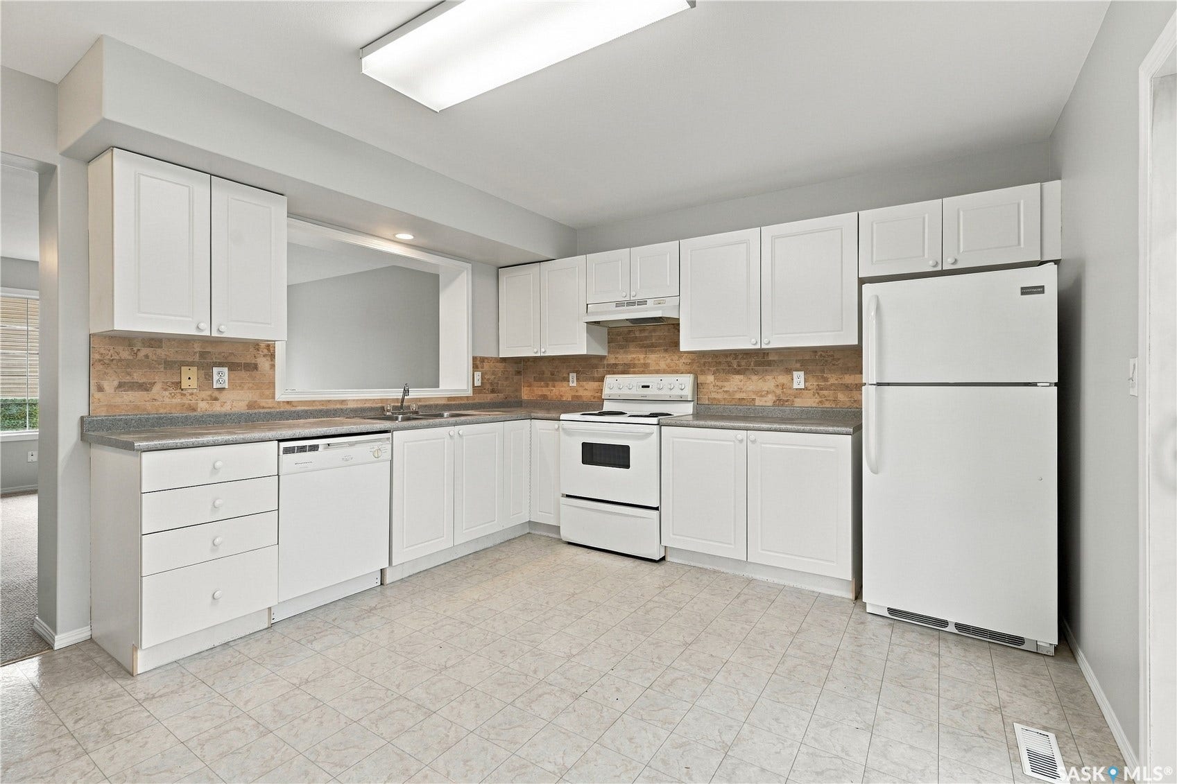 White cabinetry with matching appliances, stone-look backsplash, and a pass-through window