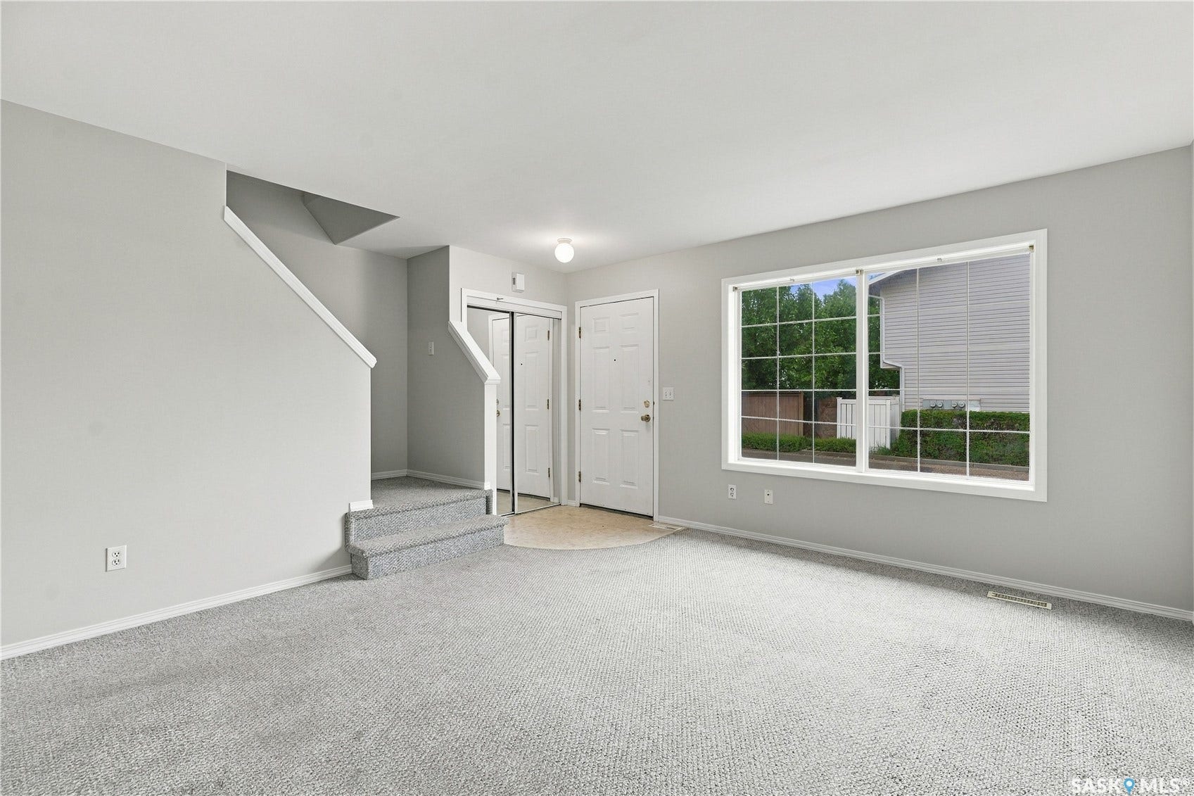 Entryway with carpeted stairs, a front door, and a large window