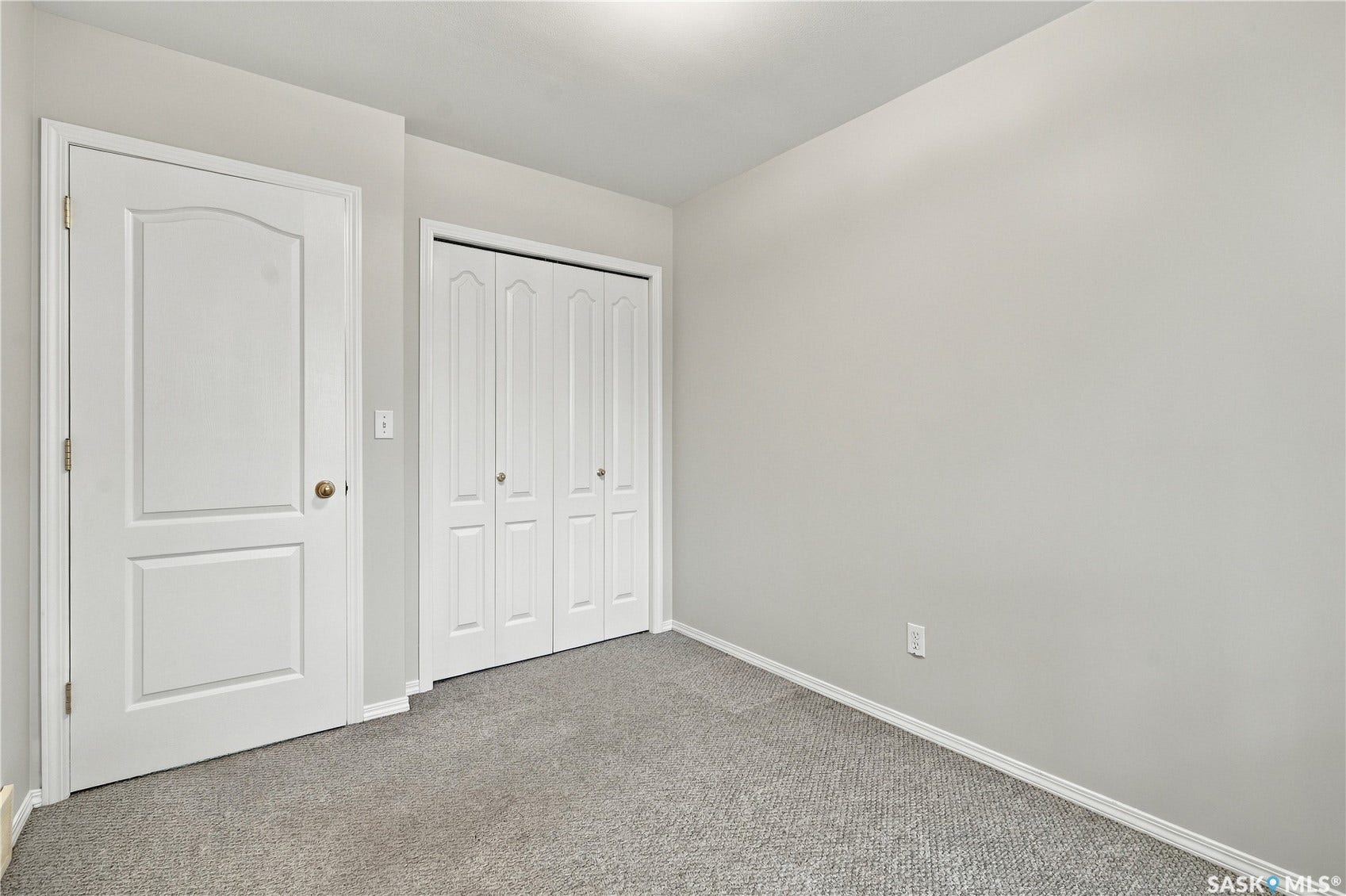 Light gray walls with white trim, gray carpet flooring, and a white interior door