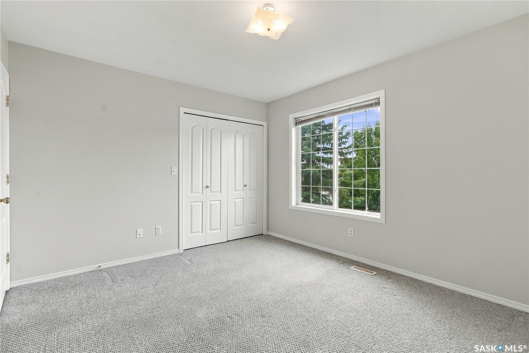 Wall-to-wall carpeting, bi-fold closet doors, and a window with white trim