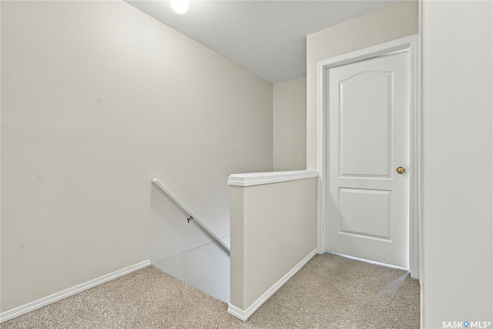 Neutral tone wall paint, carpet flooring, white interior door, and white trim accents