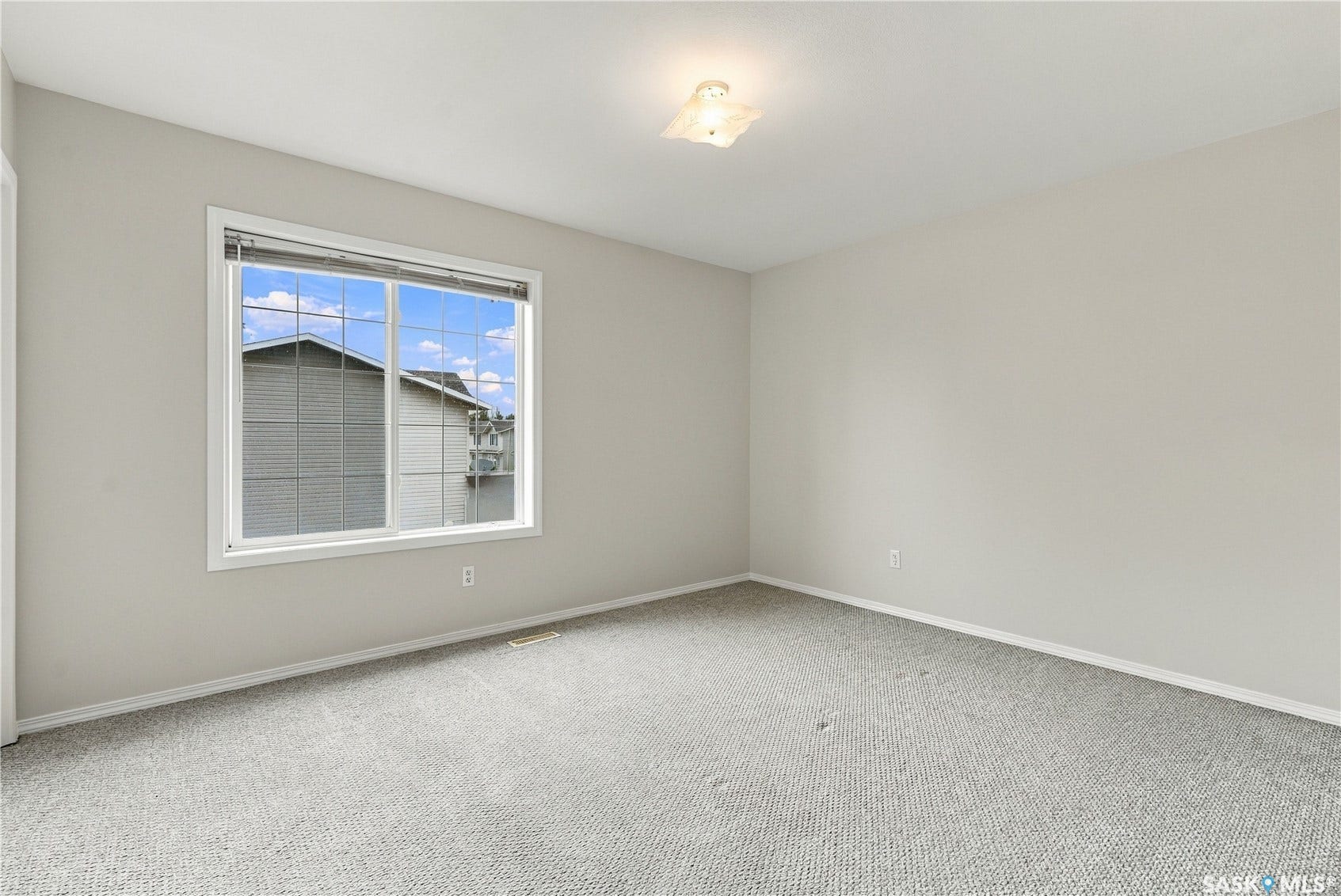 Wall-to-wall carpeting with light-toned walls, a rectangular window, and a ceiling-mounted light fixture