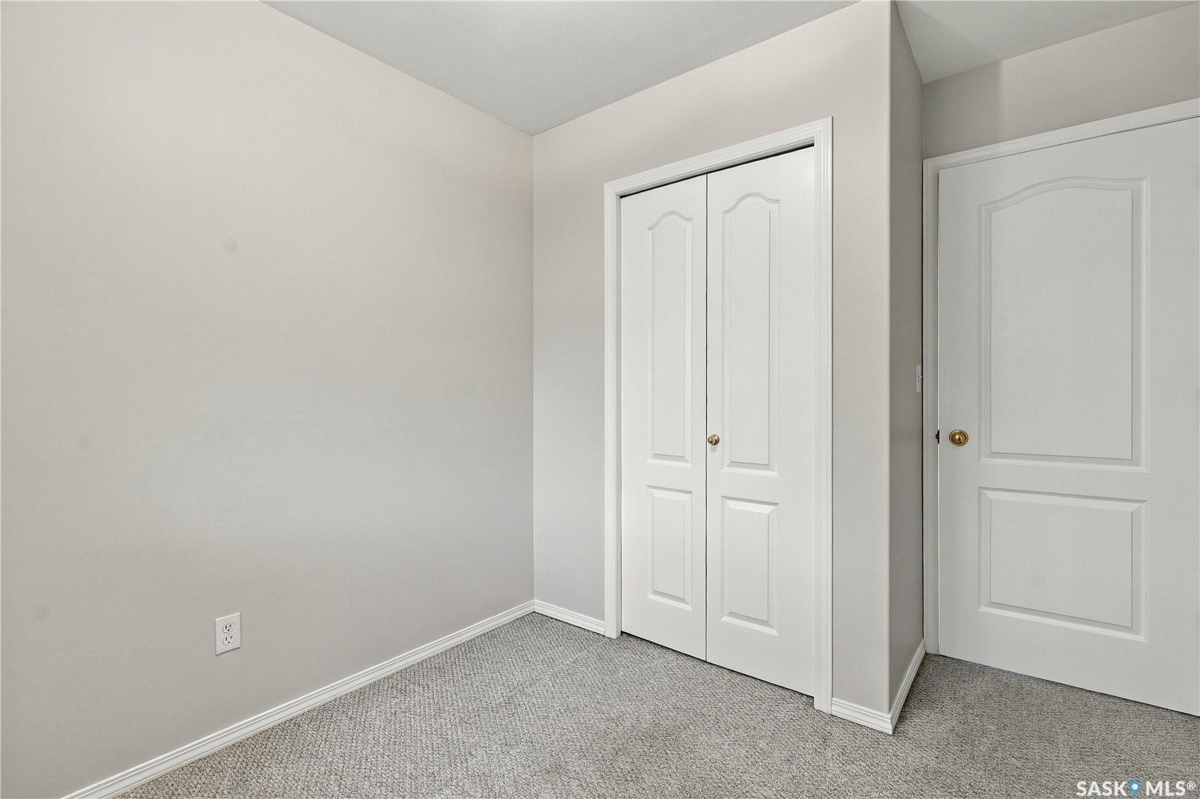 Plush carpeting, neutral wall finishes, closet with bi-fold doors, and a solid panel door with brass hardware