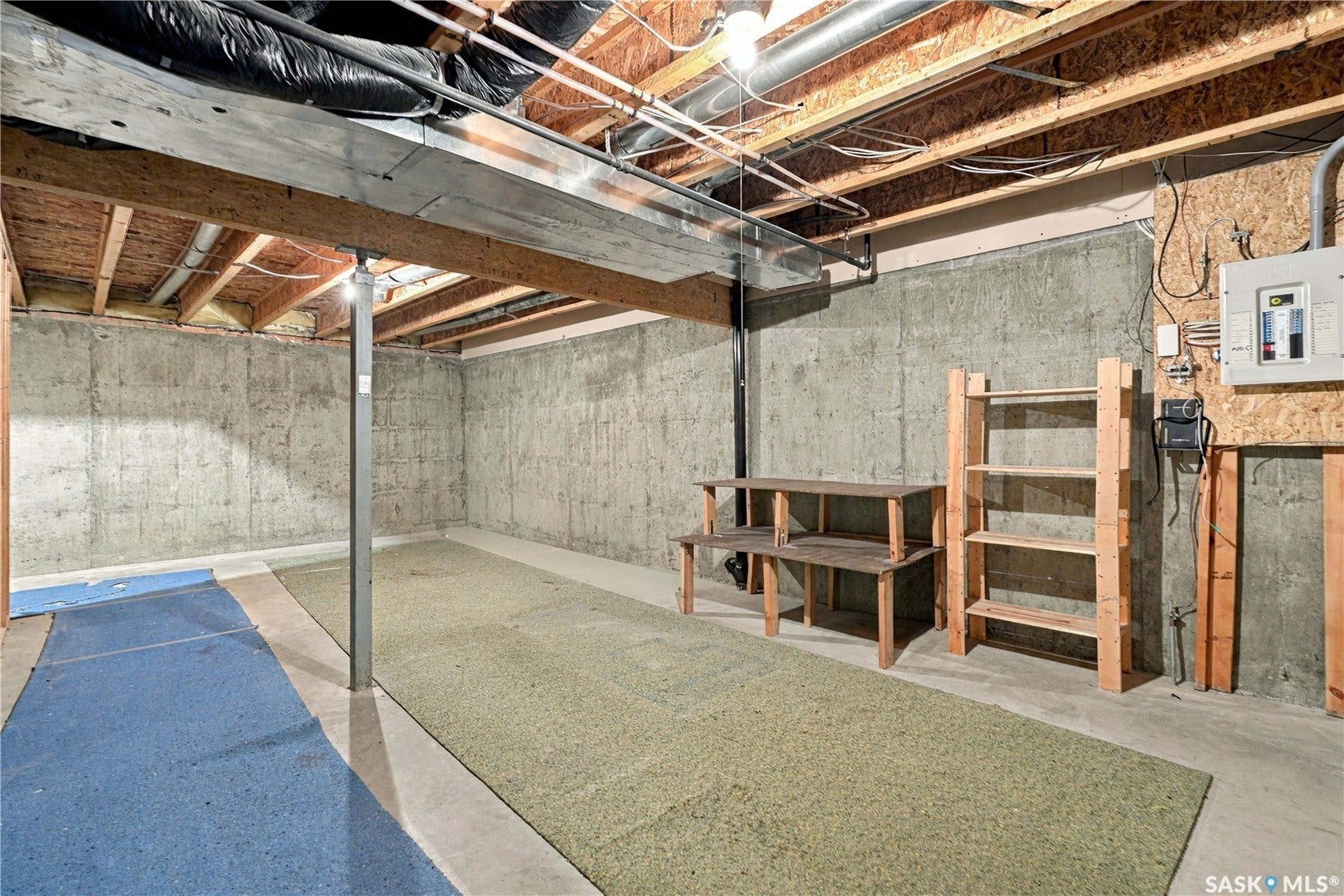 Exposed wood joist ceiling, concrete walls, concrete flooring, and an electrical panel