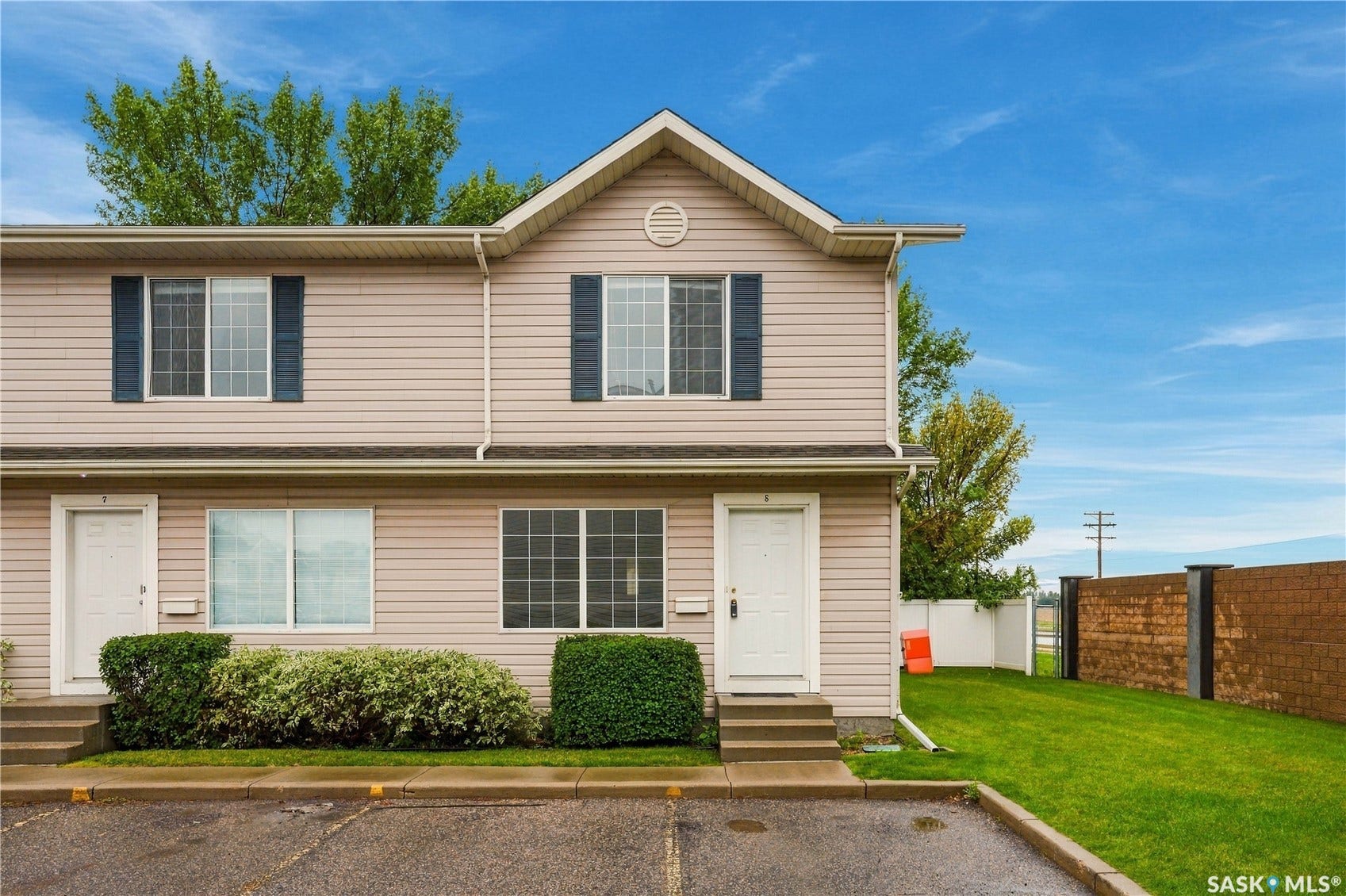 Two-story residence featuring siding exterior, an angled roofline, multiple windows with shutters, and a well-maintained lawn area