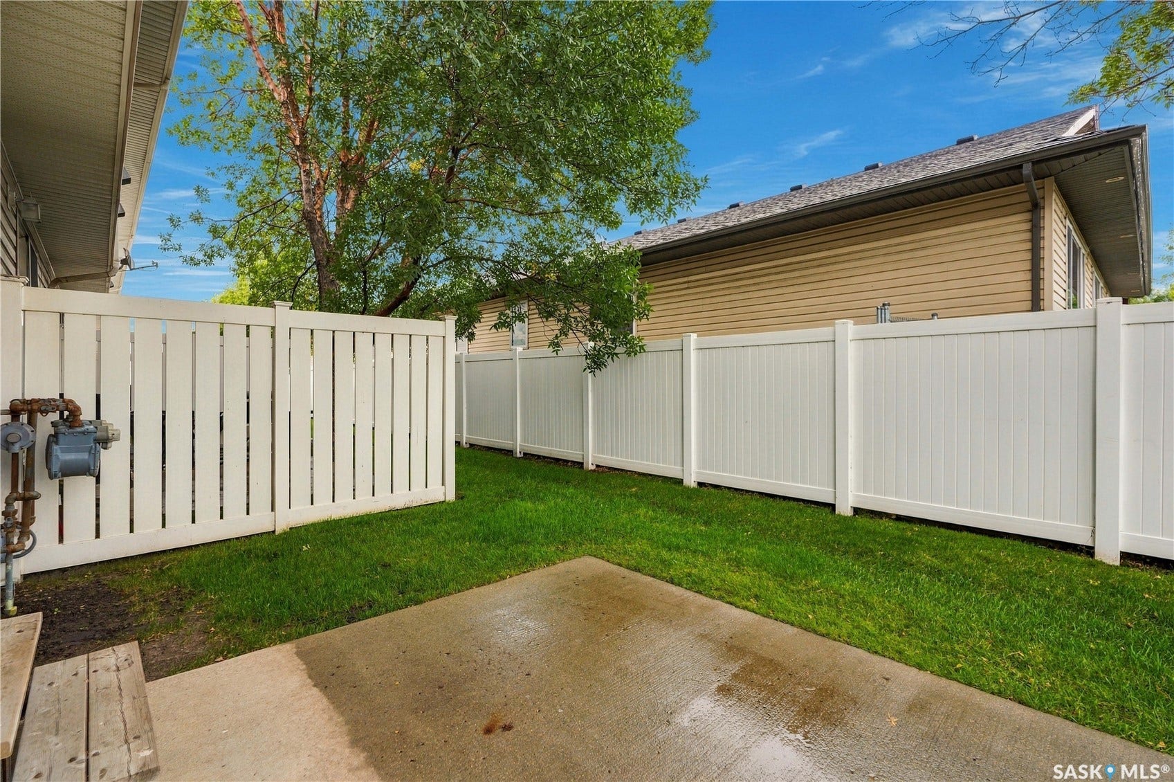 Fenced yard featuring a concrete patio and green lawn
