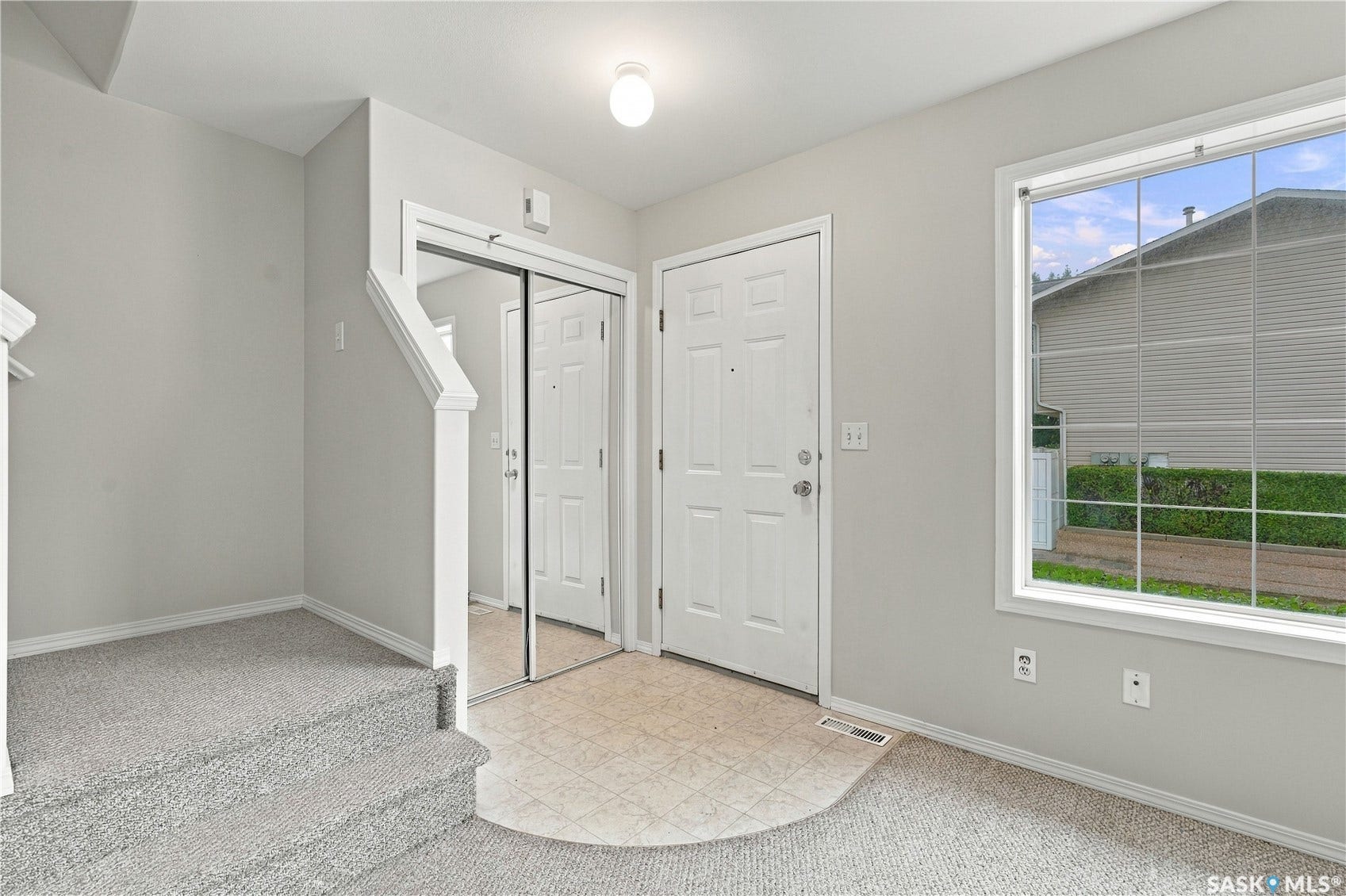 Entryway with a paneled door, a large window, and a mirrored closet