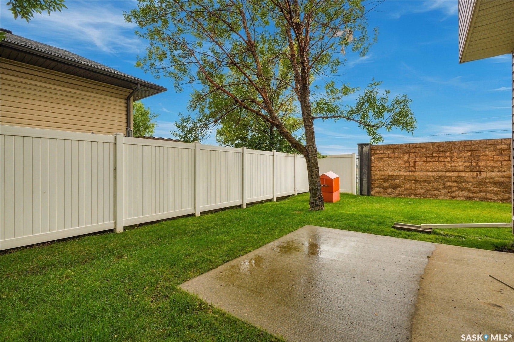 Expansive grassy area featuring a concrete patio and perimeter fencing