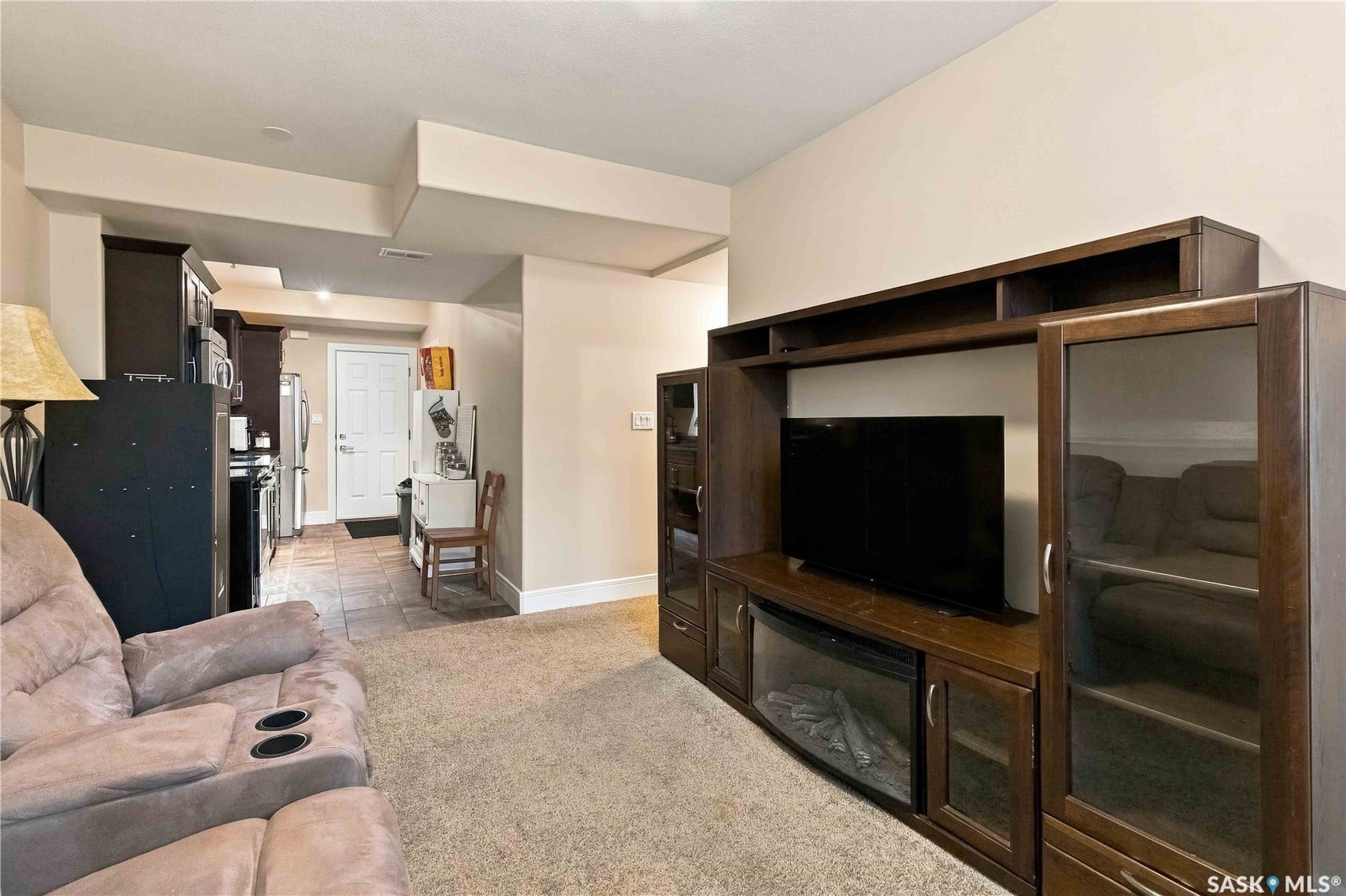 Built-in media console with fireplace, recessed lighting, and contrasting dark kitchen cabinetry
