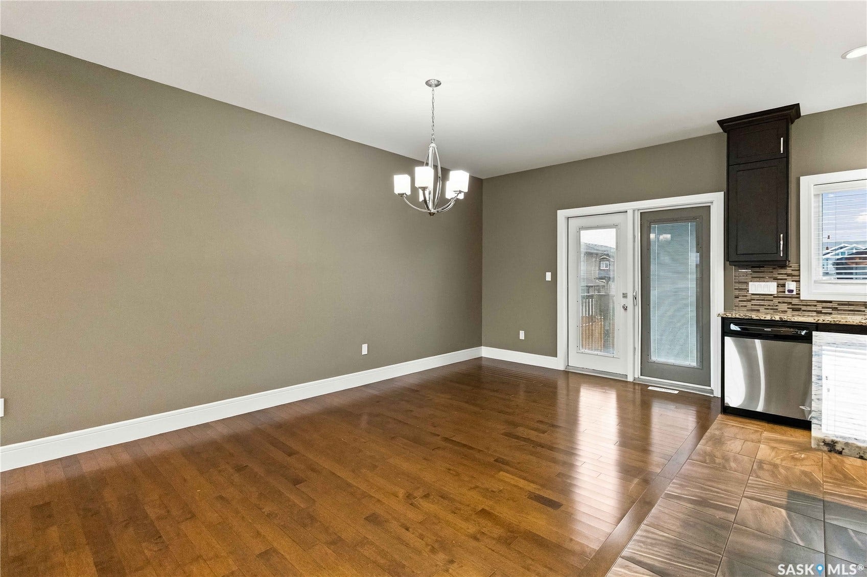 Wood-finish flooring, contemporary chandelier, sliding glass door, dark wood cabinetry, and stainless steel appliance