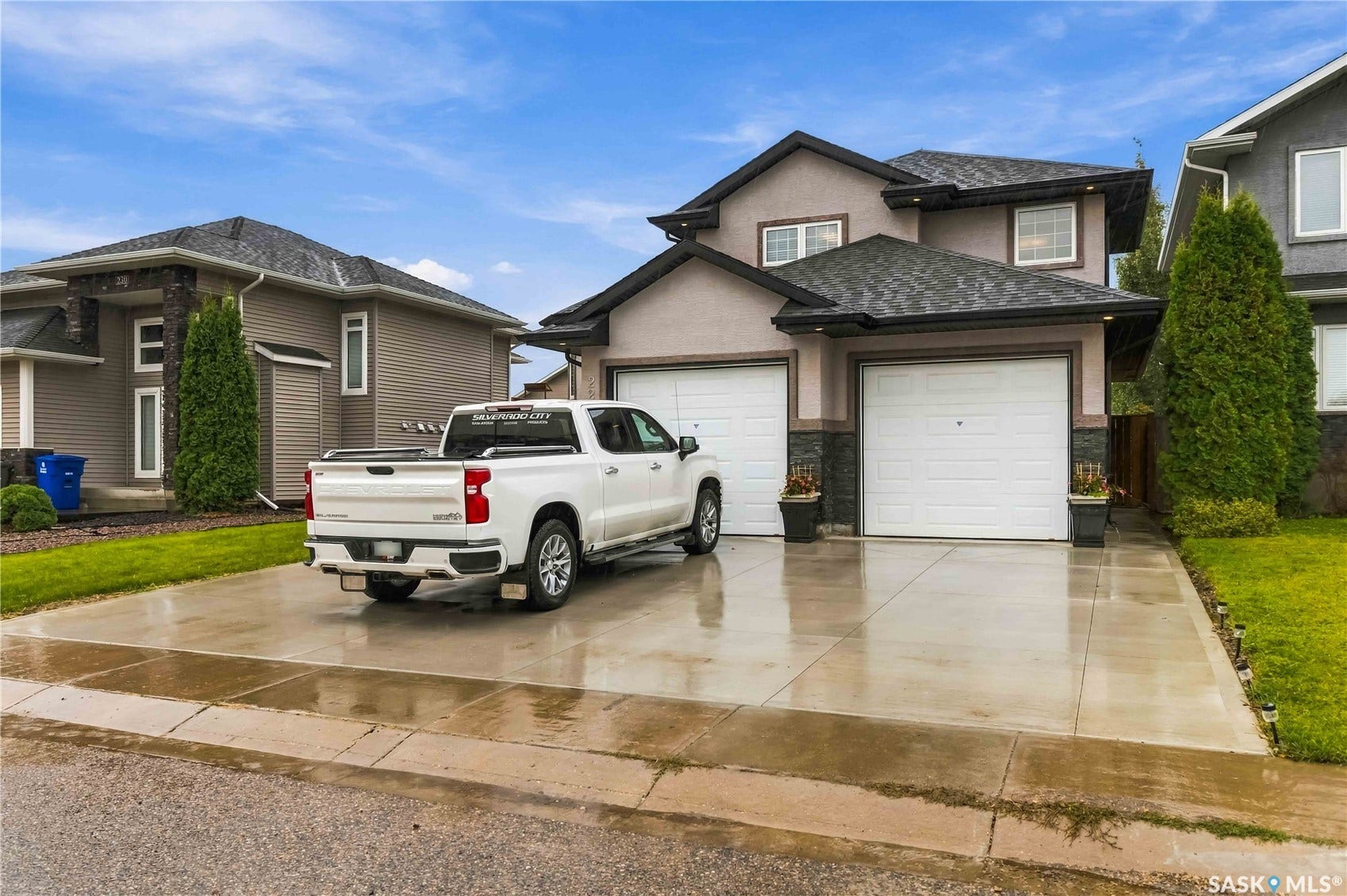 Stucco exterior with stone accents, dual garage doors, and a concrete driveway