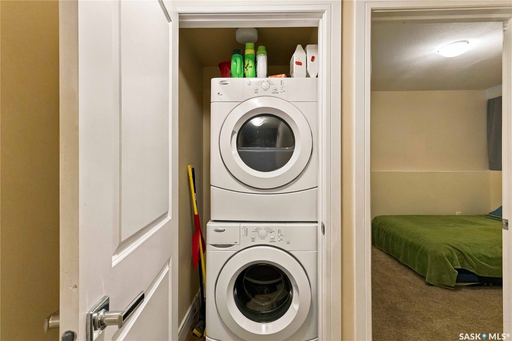 Laundry closet with stacked appliances and shelving