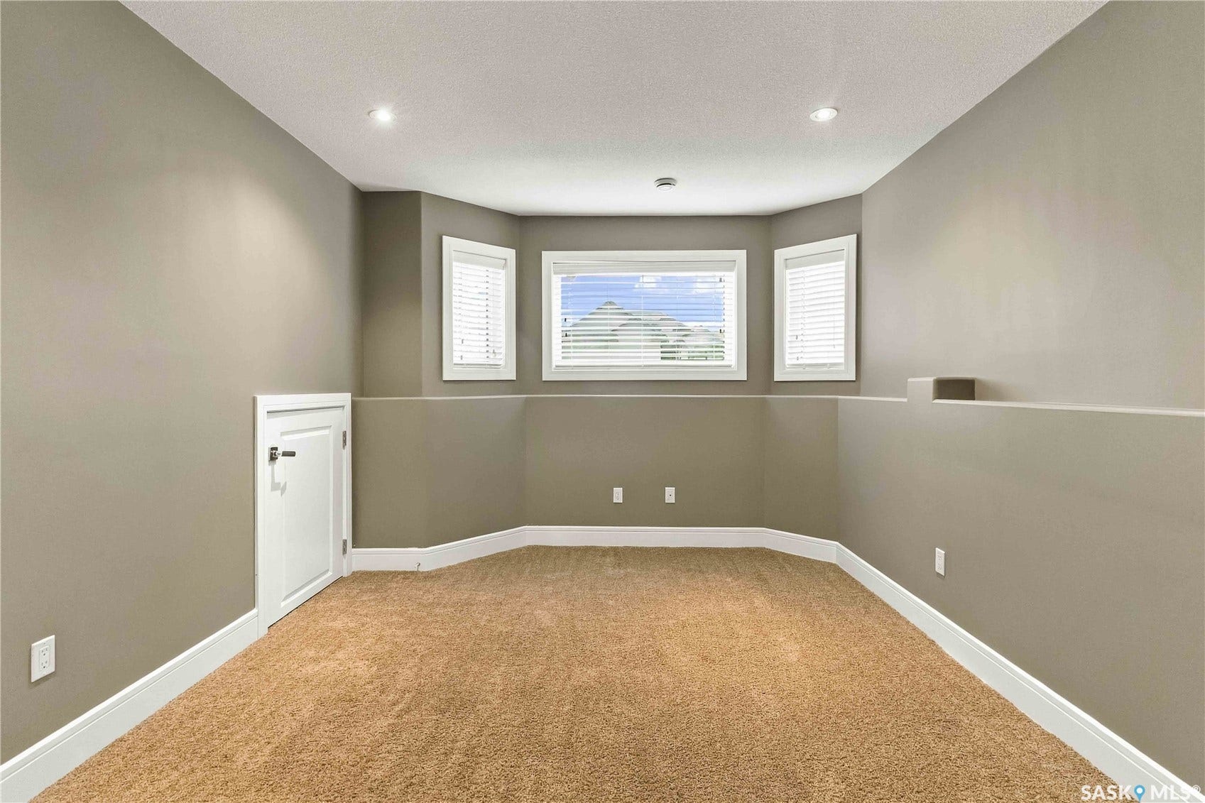 Recessed lighting, bay window, white window blinds, light brown carpeting, and a built-in storage cabinet with white trim