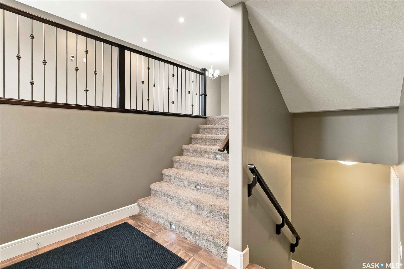 Carpeted staircase with recessed lighting, dark wood handrail, and wrought iron balustrade