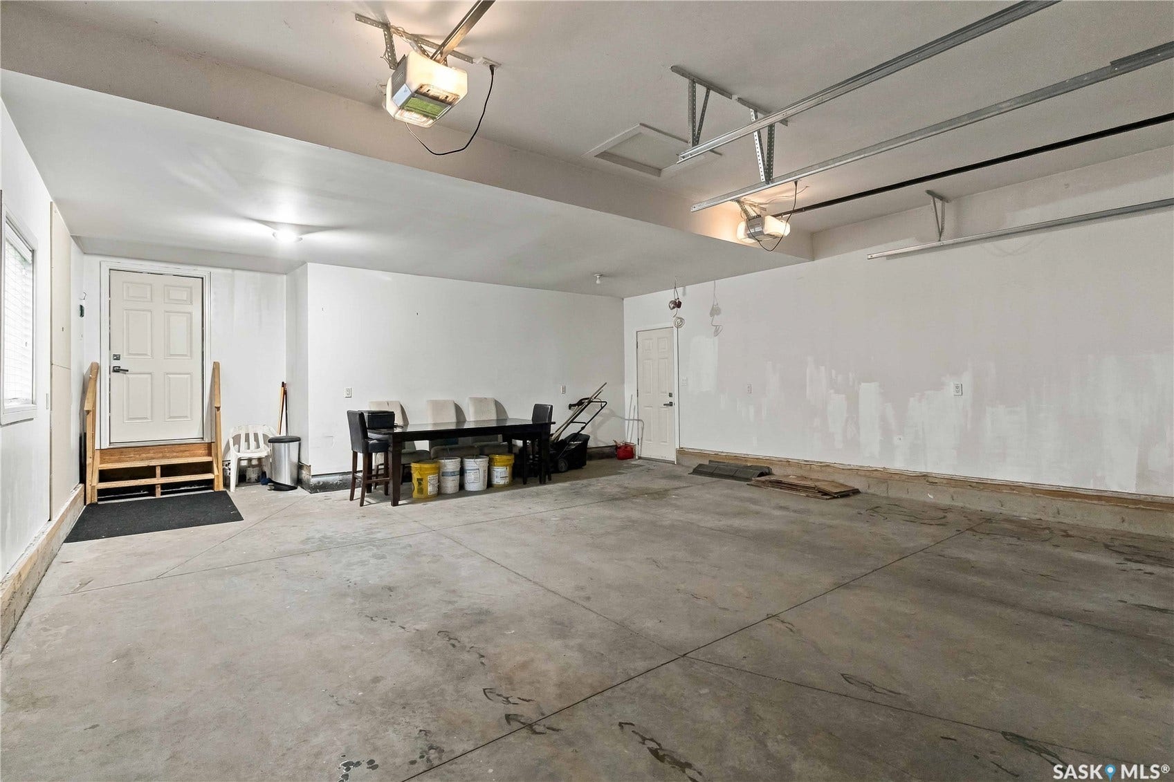 Concrete flooring, exposed ceiling rails, overhead lighting, door access, and a window