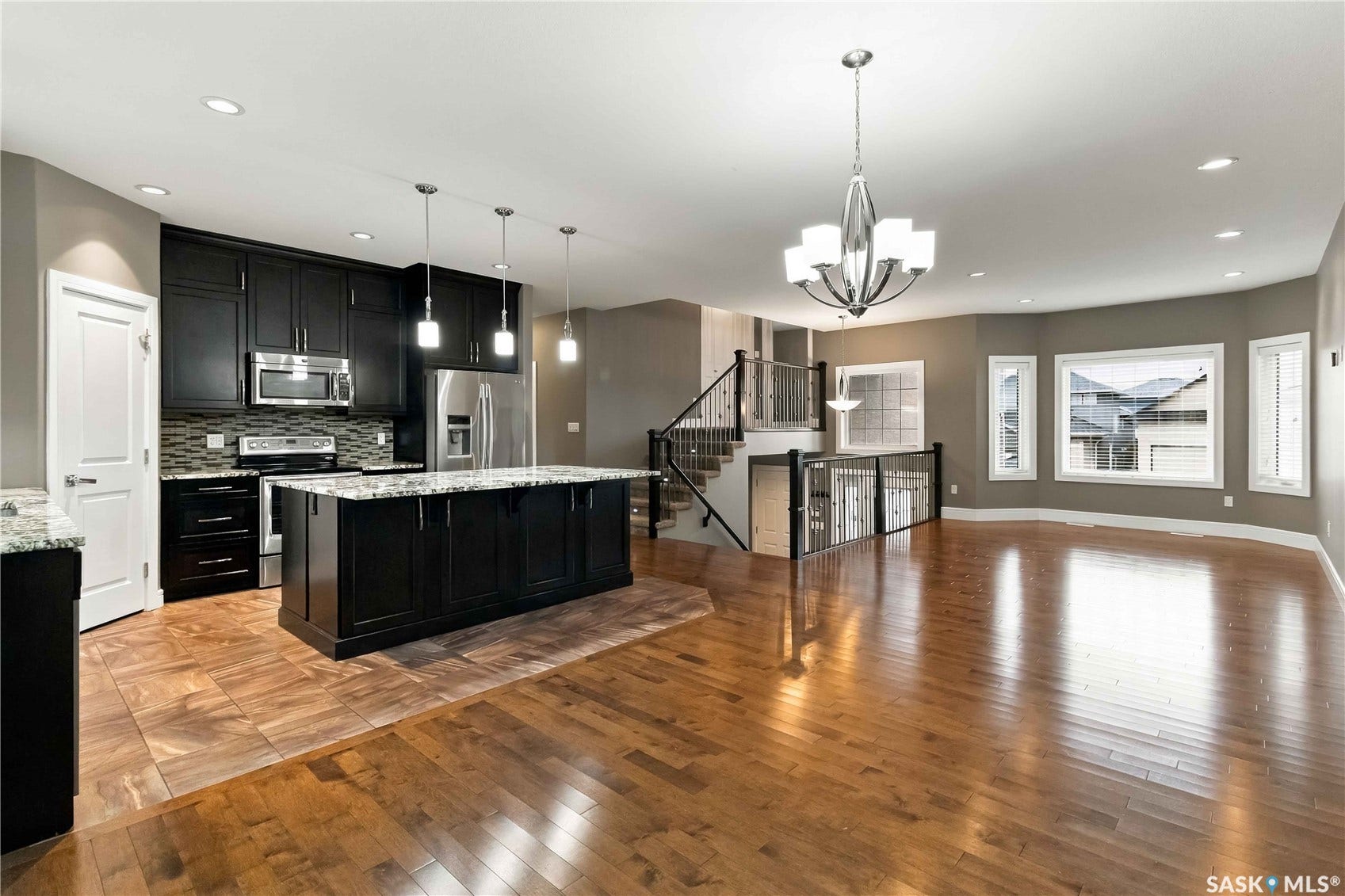 Kitchen featuring dark cabinetry, stainless steel appliances, and a large central island with pendant lighting
