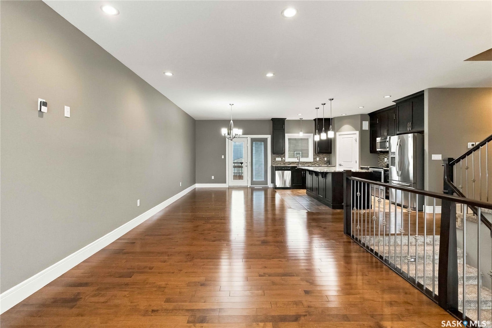 Open-concept living space with wood-finish flooring, recessed lighting, and a neutral wall color