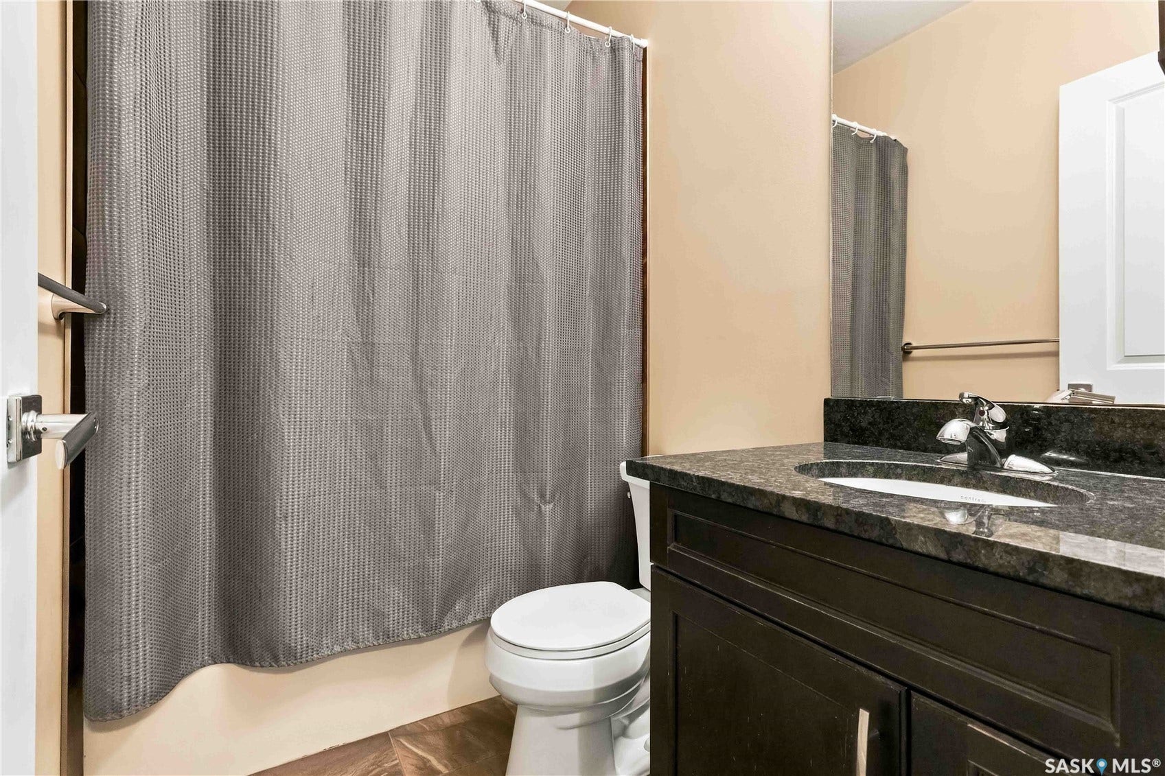 Dark stone countertop with an integrated sink, complementing a dark wood-finish vanity