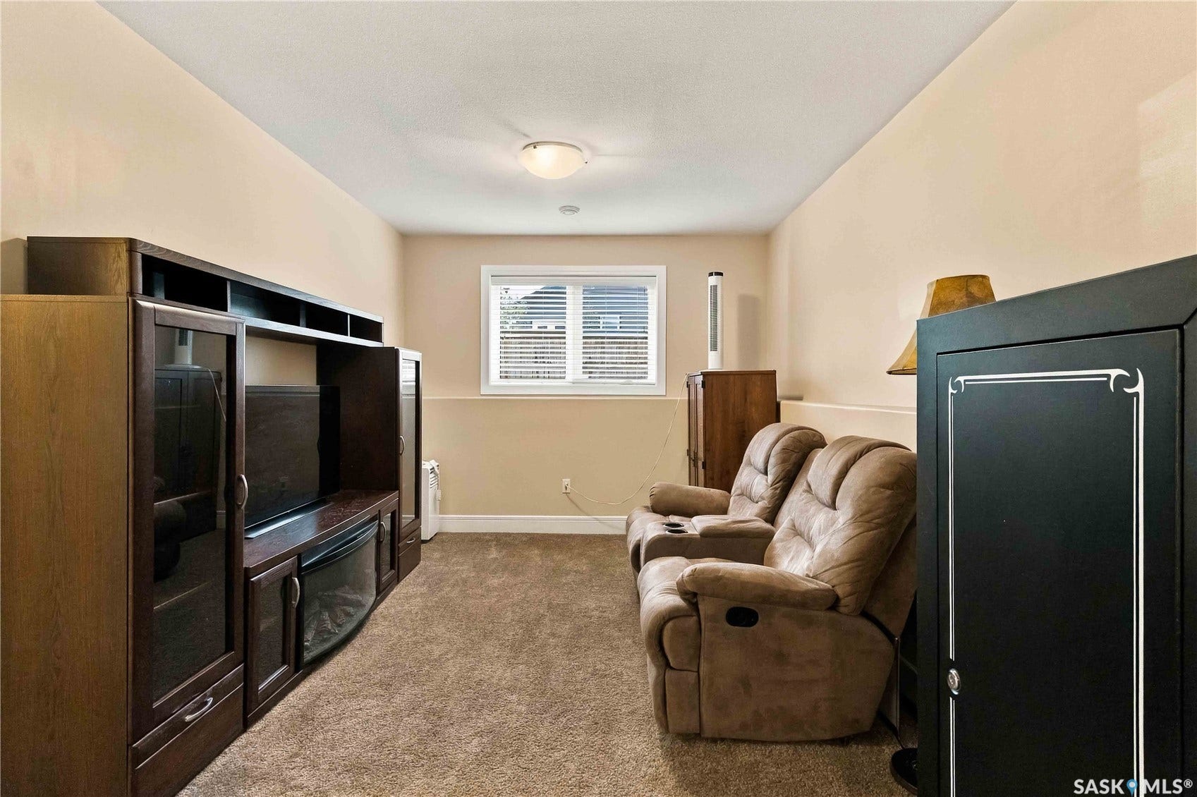 Carpeted floor, neutral wall tones, recessed lighting, and a built-in media console with glass-front cabinetry