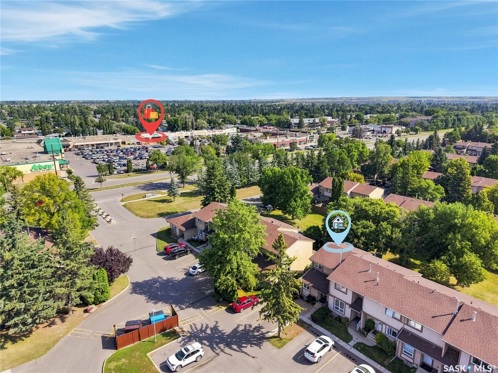 Residential complex with mature trees, paved parking areas, and adjacent commercial establishments