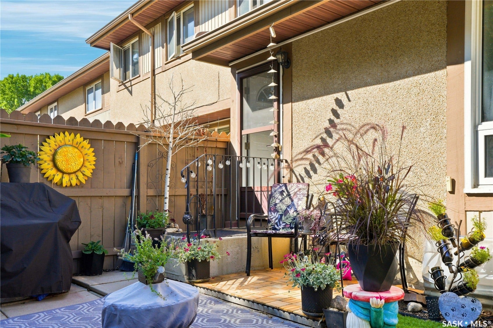 Covered patio with composite decking and black metal railings, complemented by mature landscaping with ornamental grasses and perennial plantings