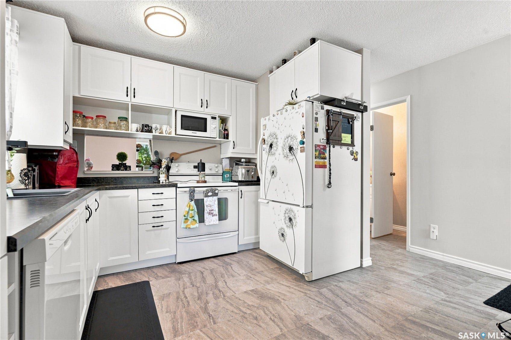 Kitchen featuring white cabinetry, dark countertops, white appliances, and light flooring