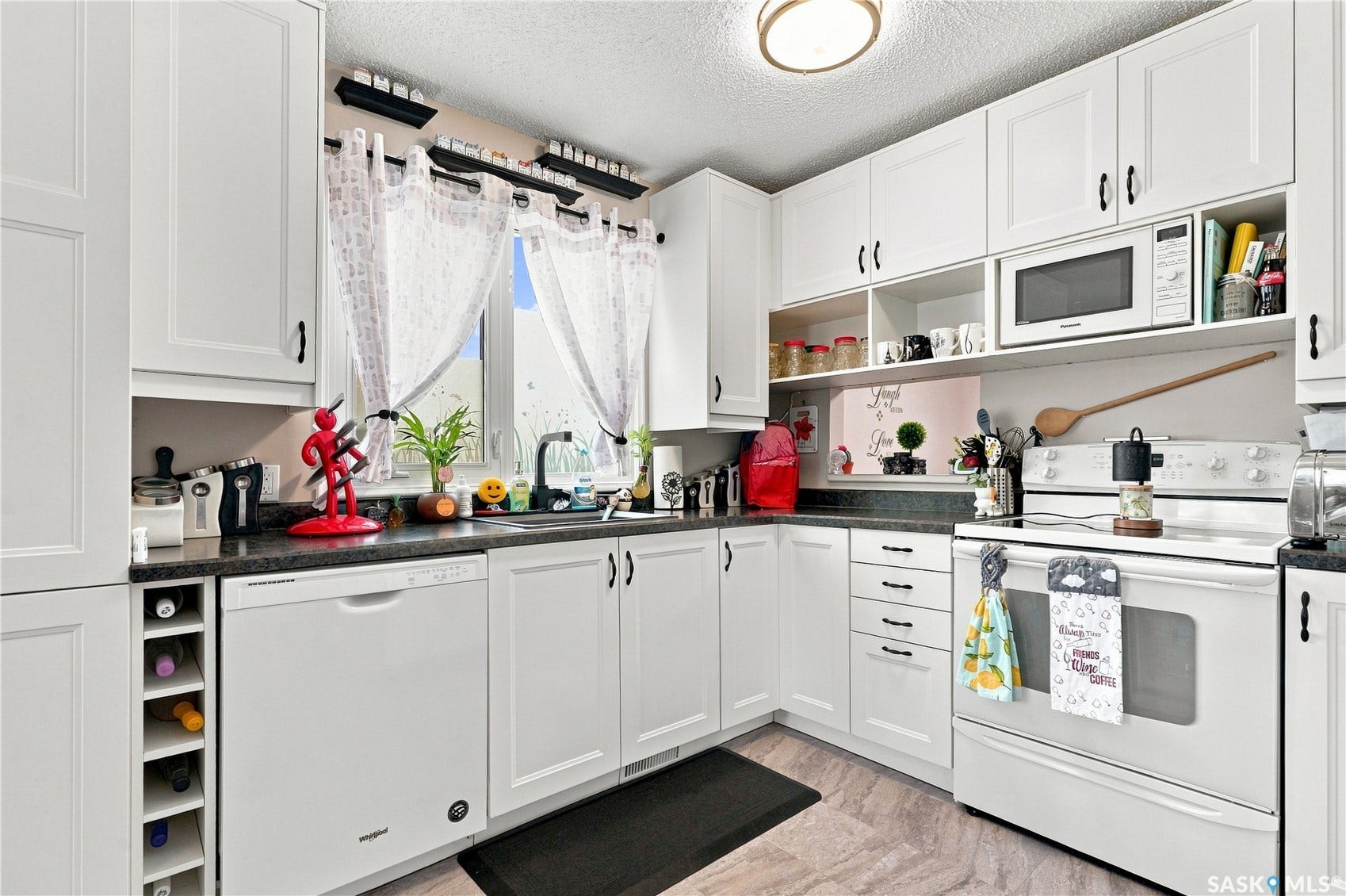 Kitchen featuring white cabinetry, dark countertops, a built-in dishwasher, white range, and a ceiling-mounted light fixture