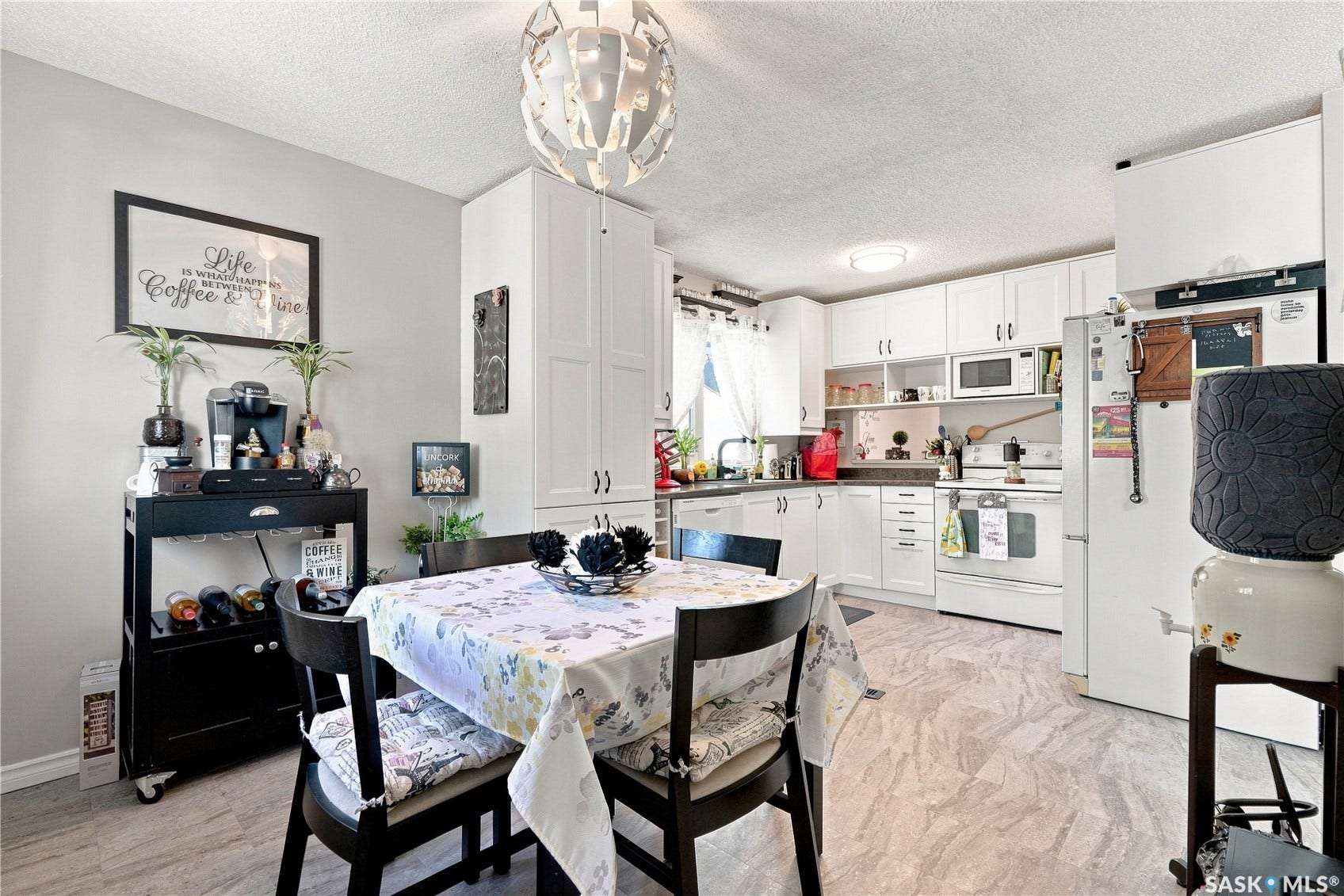 White kitchen cabinetry with dark countertops, white appliances, and light flooring