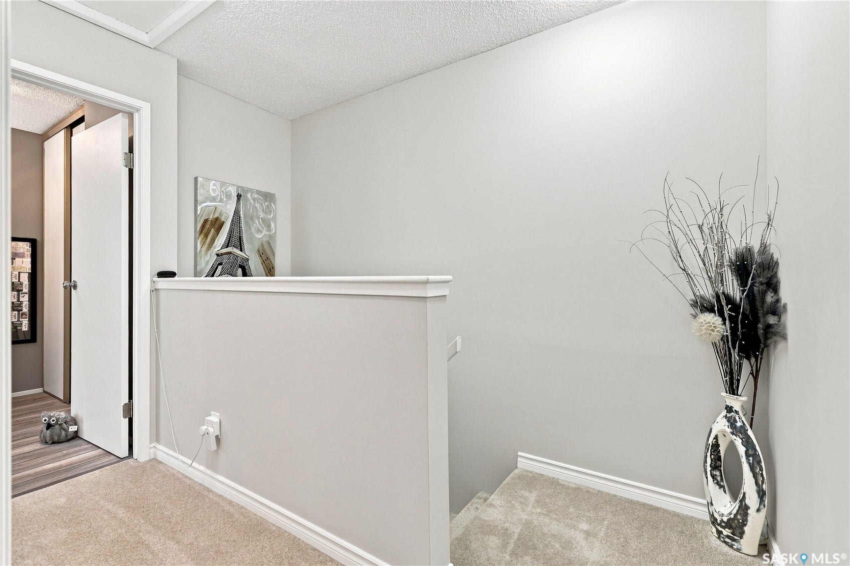 Carpeted stairway with a neutral color palette, white trim, and a textured ceiling
