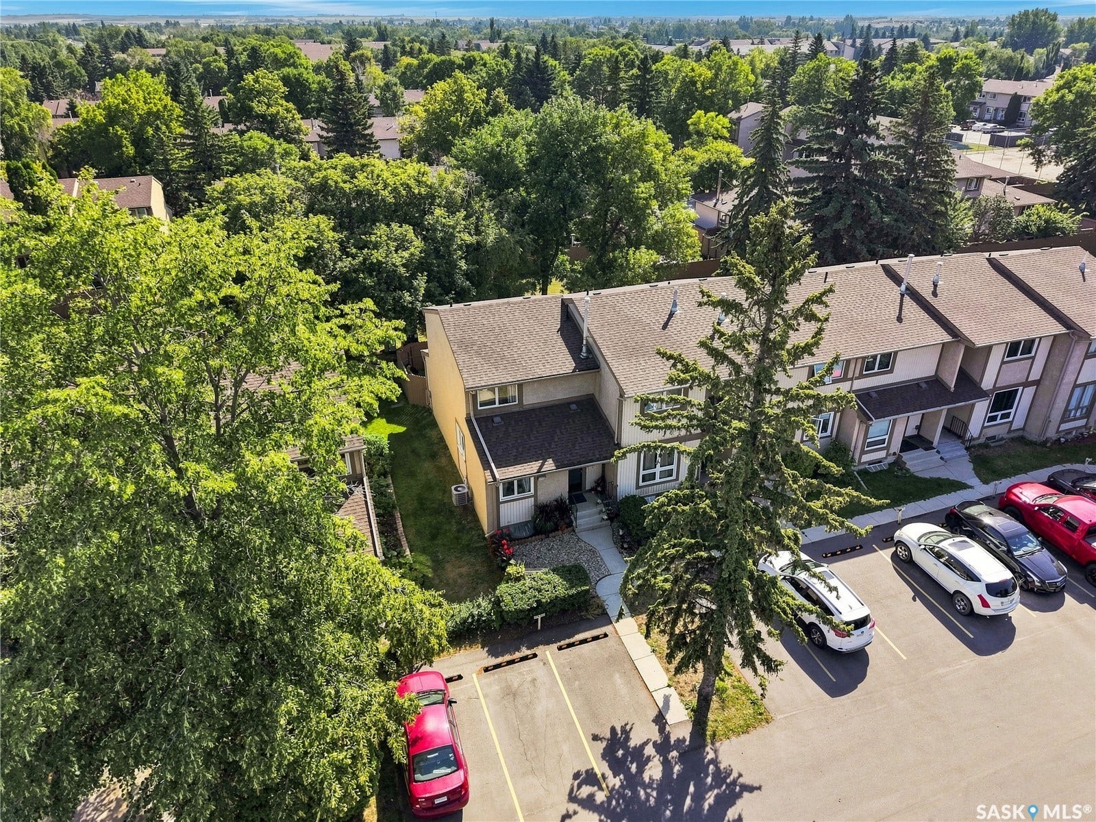 Townhome exterior with a pitched roof, front entry pathway, and dedicated parking spaces