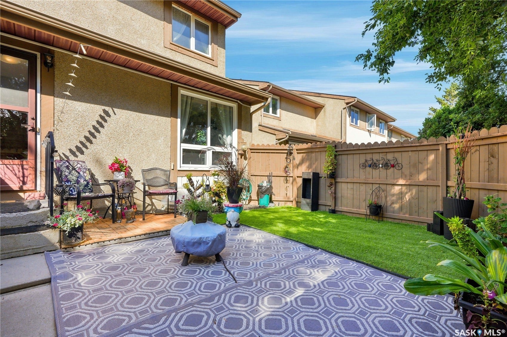 Private backyard featuring a paved patio, manicured lawn, and wood privacy fencing