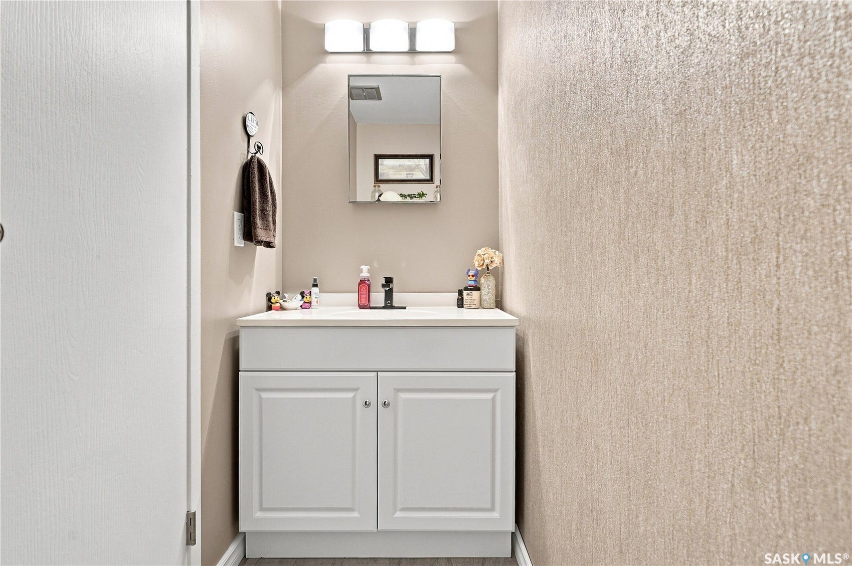 White vanity with shaker-style cabinetry, a white countertop, and a matte black faucet
