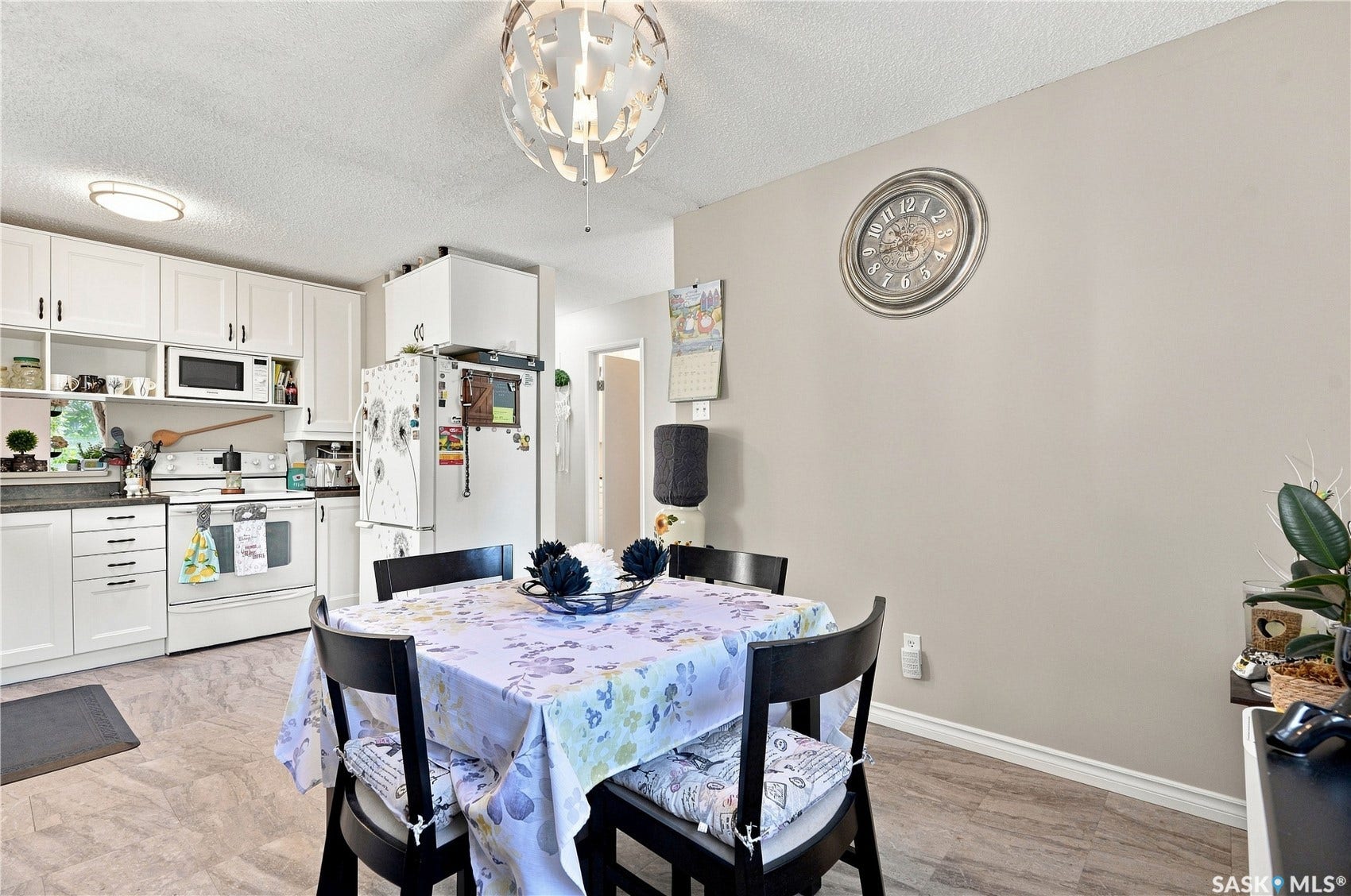 Kitchen with white cabinetry, dark countertops, white appliances, and light flooring