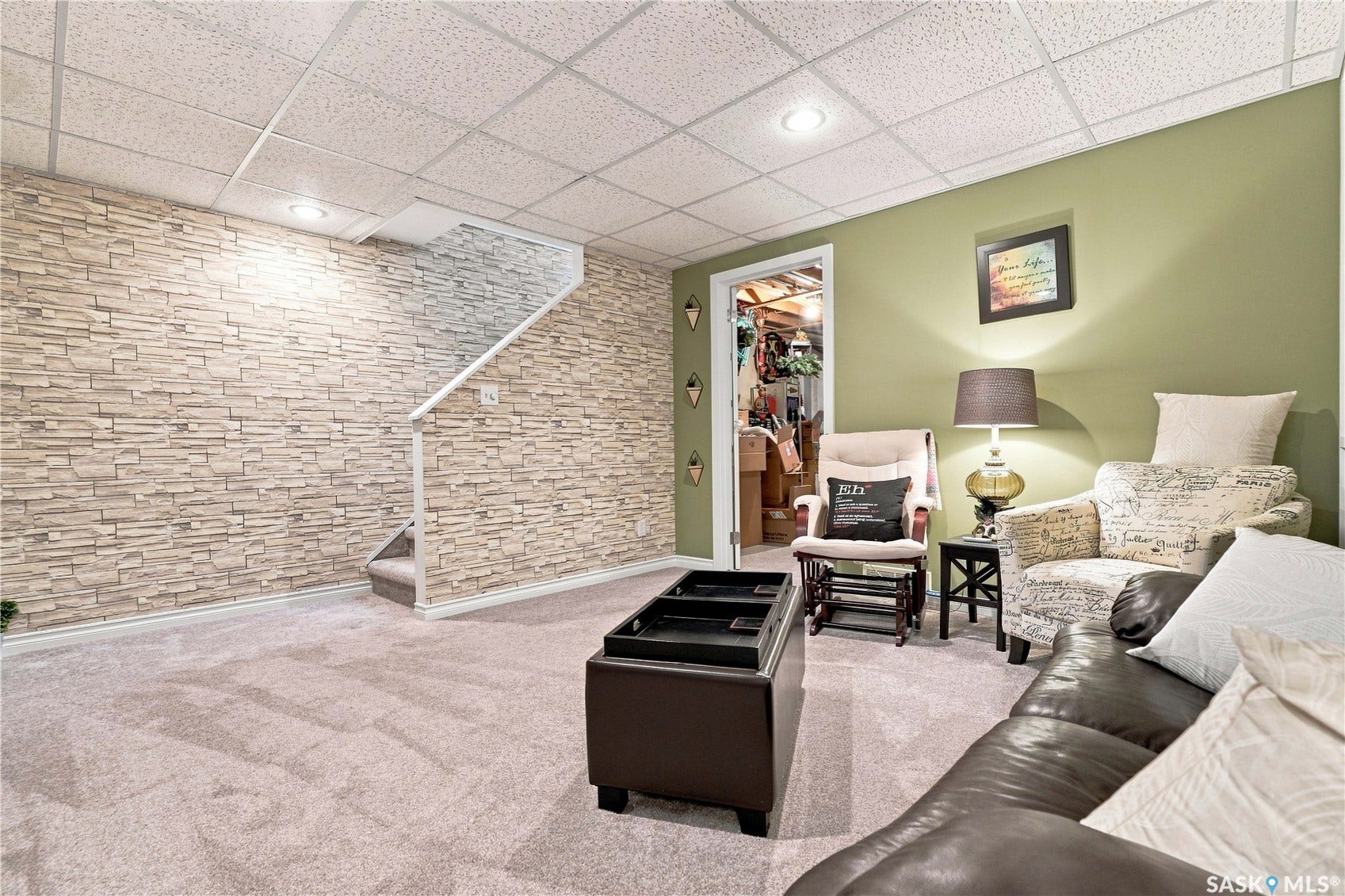 Recessed lighting, drop ceiling, wall-to-wall carpeting, stone-finish accent wall, and a staircase with a white handrail