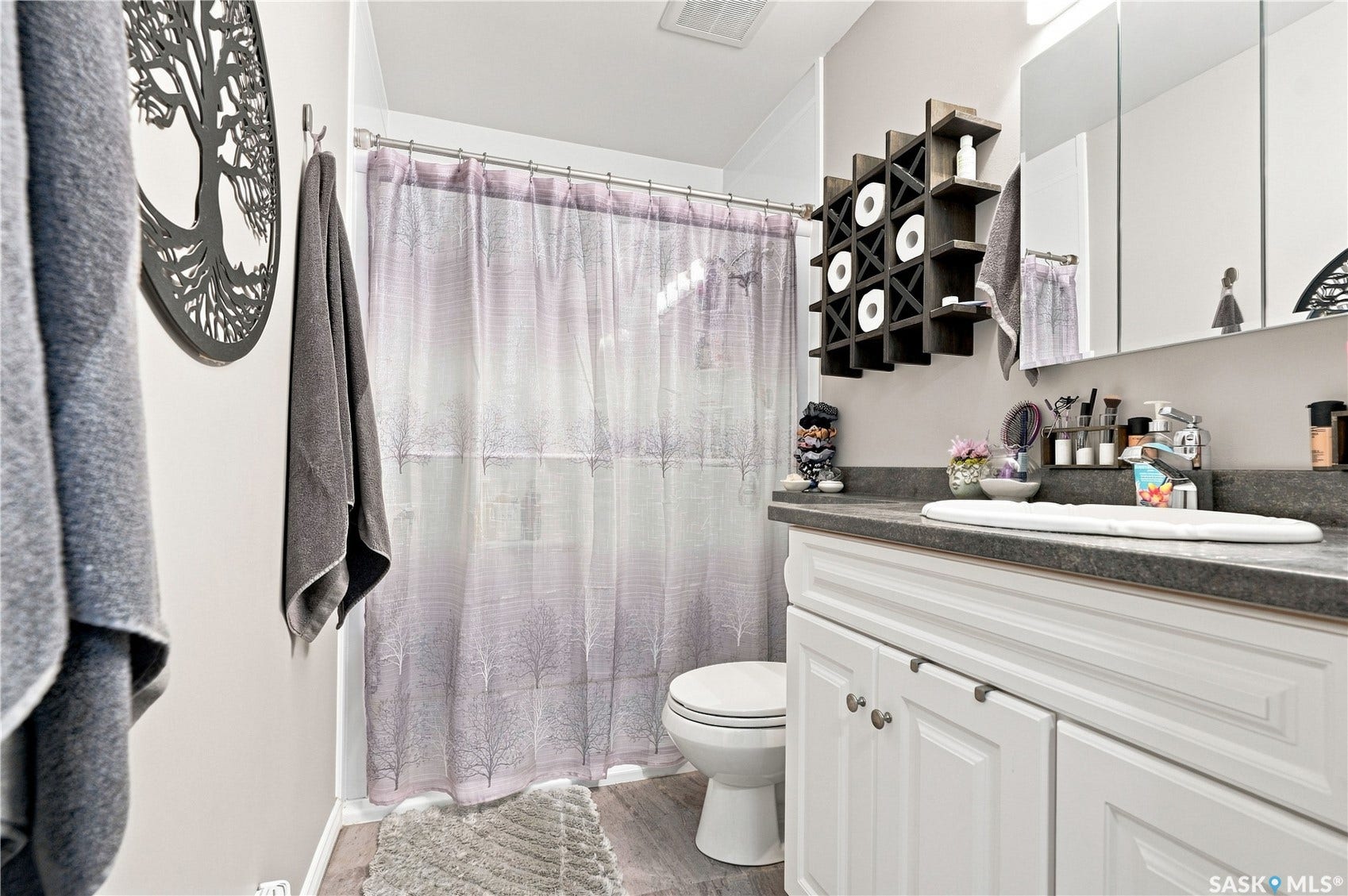 White vanity with cabinet storage, dark stone-finish countertop, and integrated sink
